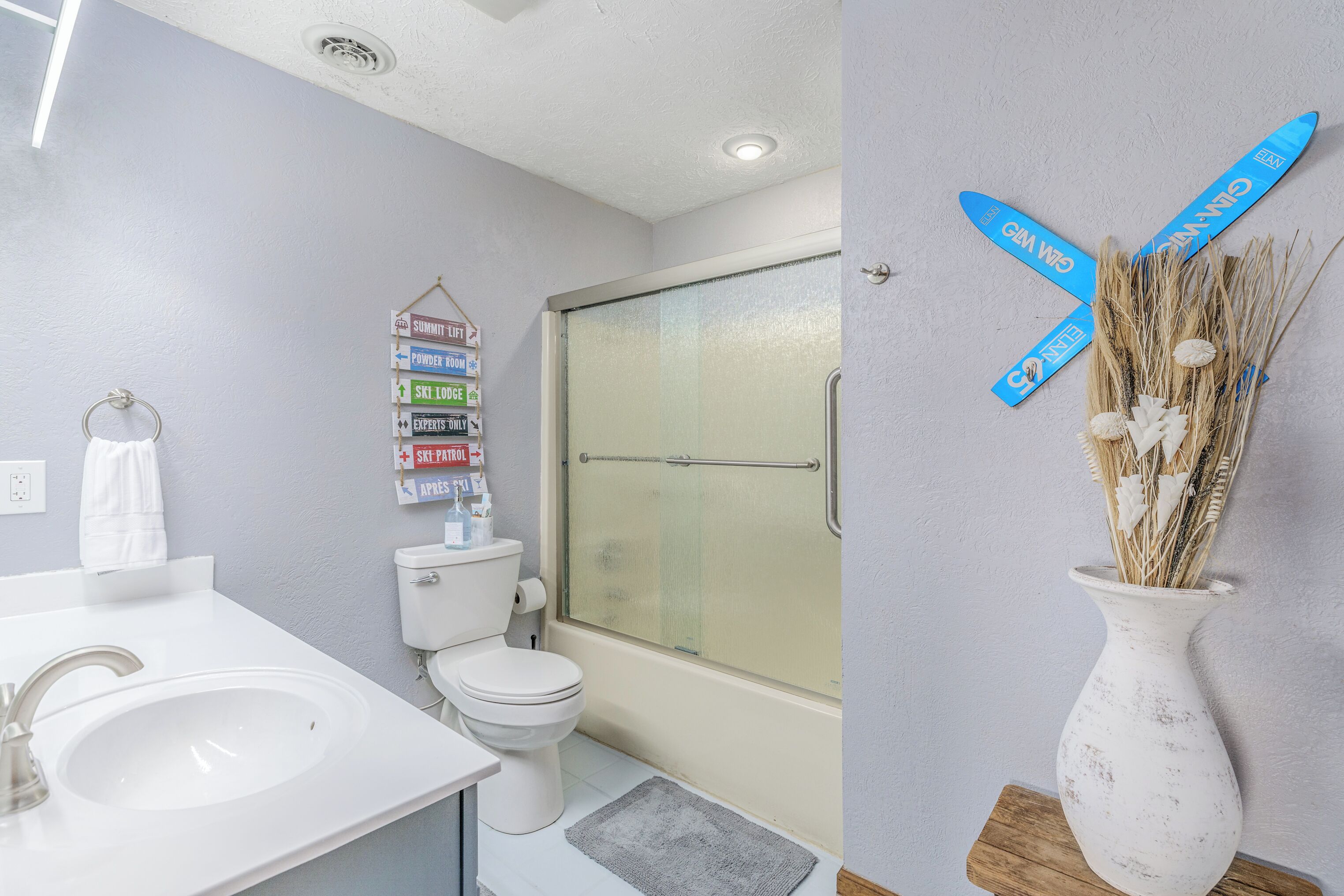 Bright full bathroom with shower/tub combo and playful ski-inspired décor.