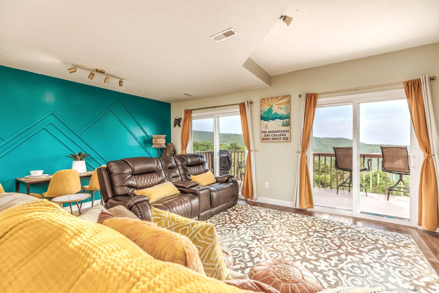 The two expansive sliding glass doors frame breathtaking panoramic mountain views, filling the living room with natural light. Relax on the comfortable sofa and take in the stunning scenery from the comfort of the chalet.