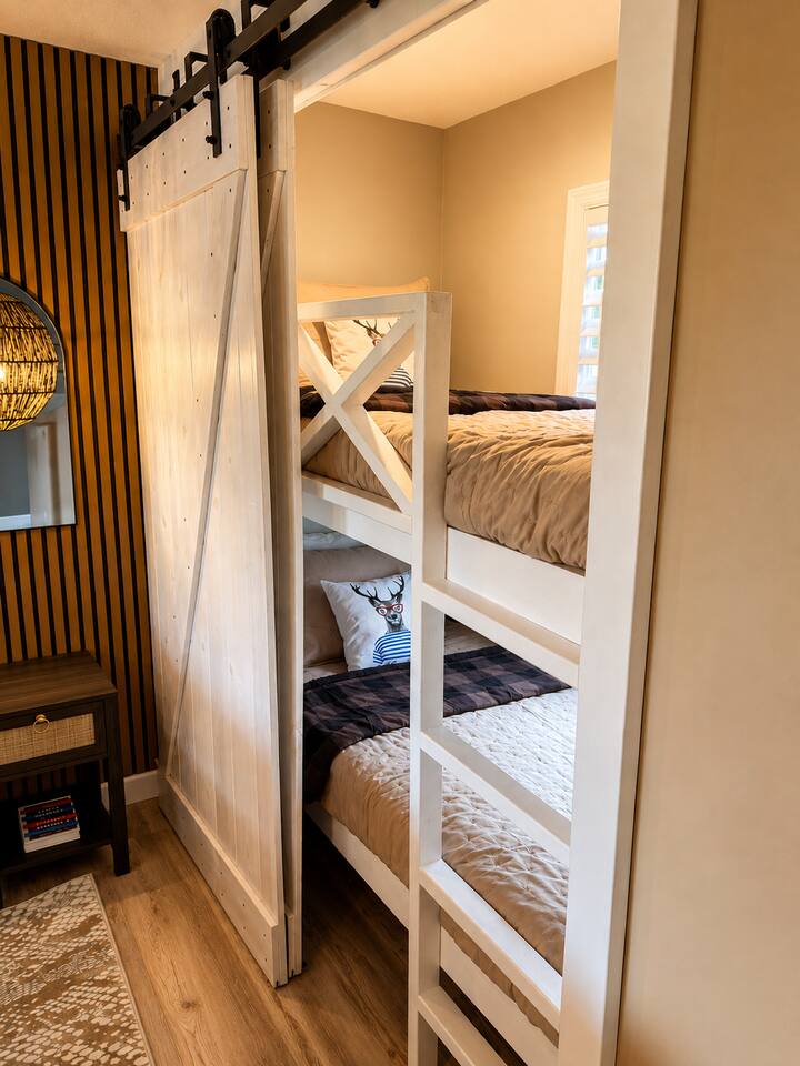 The luxurious primary suite also features thoughtfully tucked-away built-in bunks, offering a cozy and elegant retreat for children while keeping the whole family comfortably together.