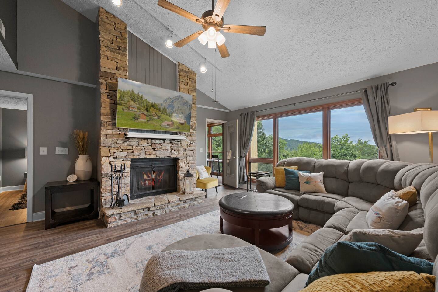 Bring the family together in this spacious mountain living room featuring a cozy stone fireplace, large sectional, Smart TV, and gorgeous Smoky Mountain views—perfect for movie nights, games, and relaxing after a day in Gatlinburg!