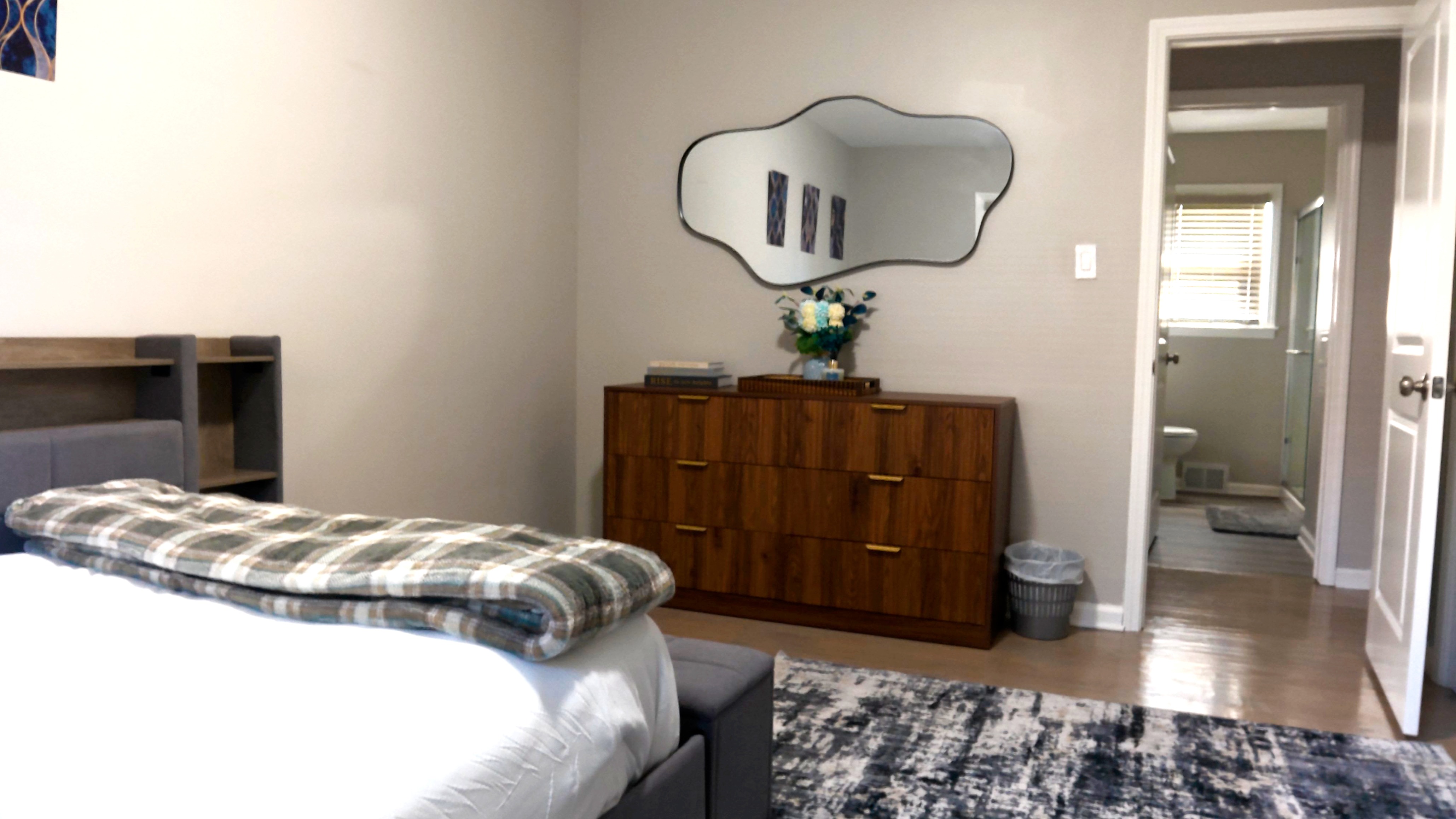 Modern bedroom with en-suite bath, stylish dresser, and cozy touches