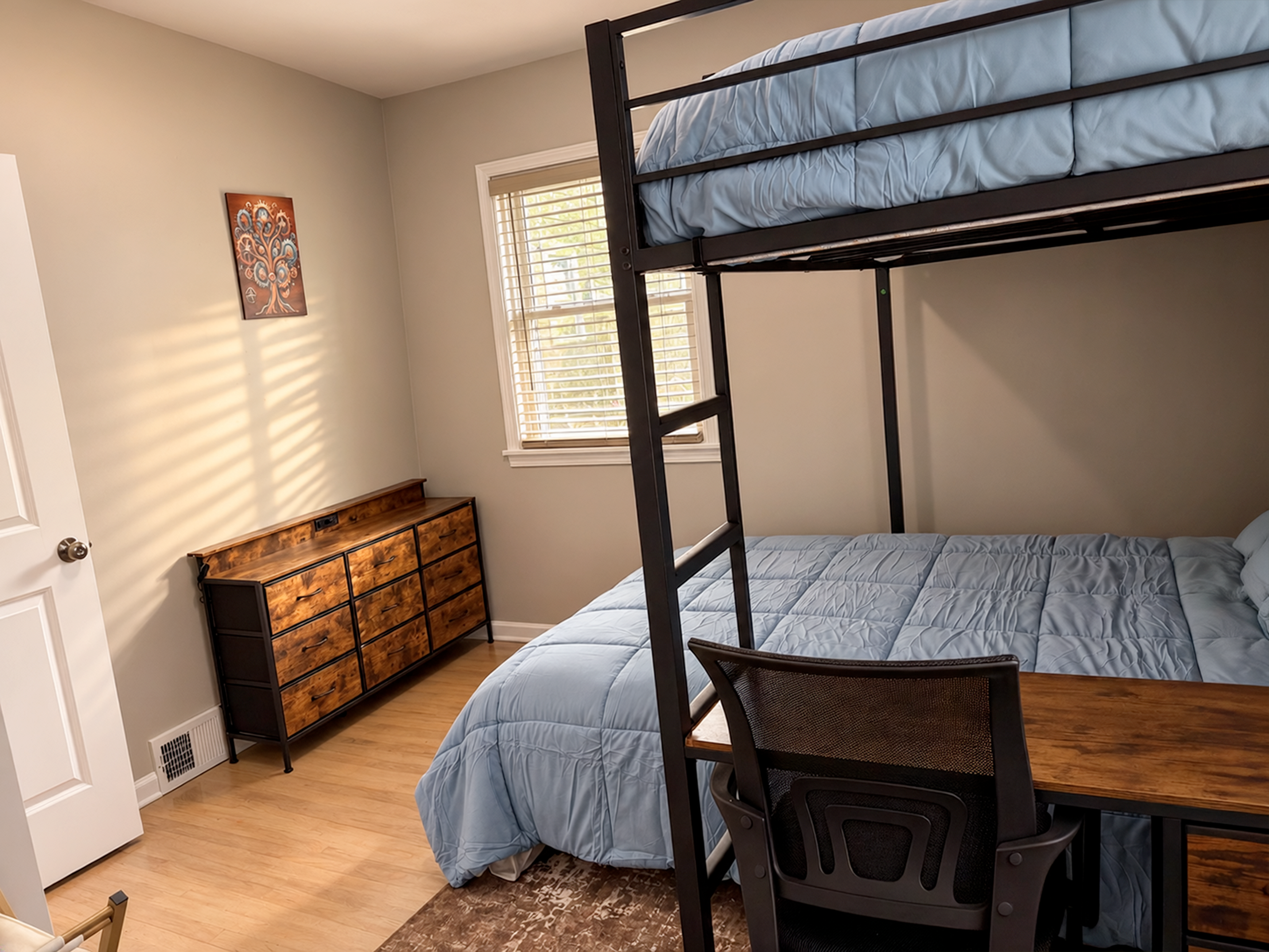Bright bunk room with desk, dresser, and cozy bedding for extra guests