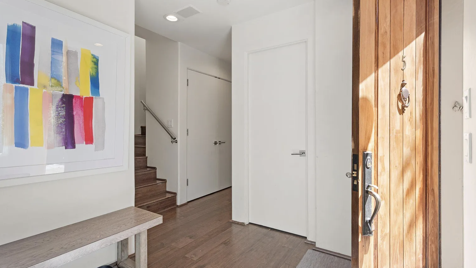 Bright modern entryway with warm wood accents and stylish artwork