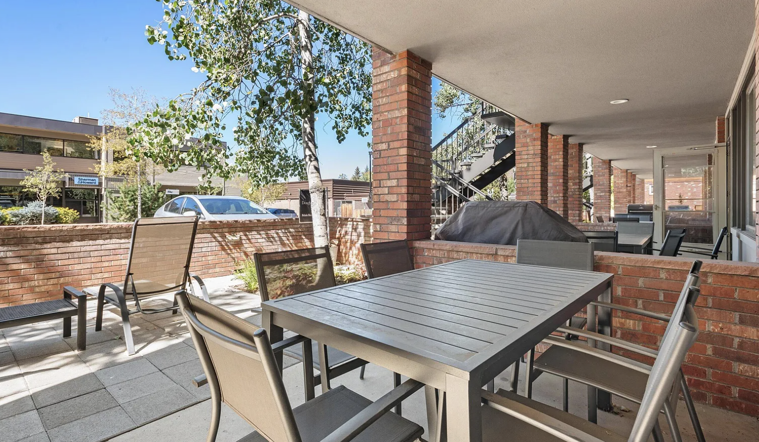 Covered patio with dining table, lounge seating, and built-in grill