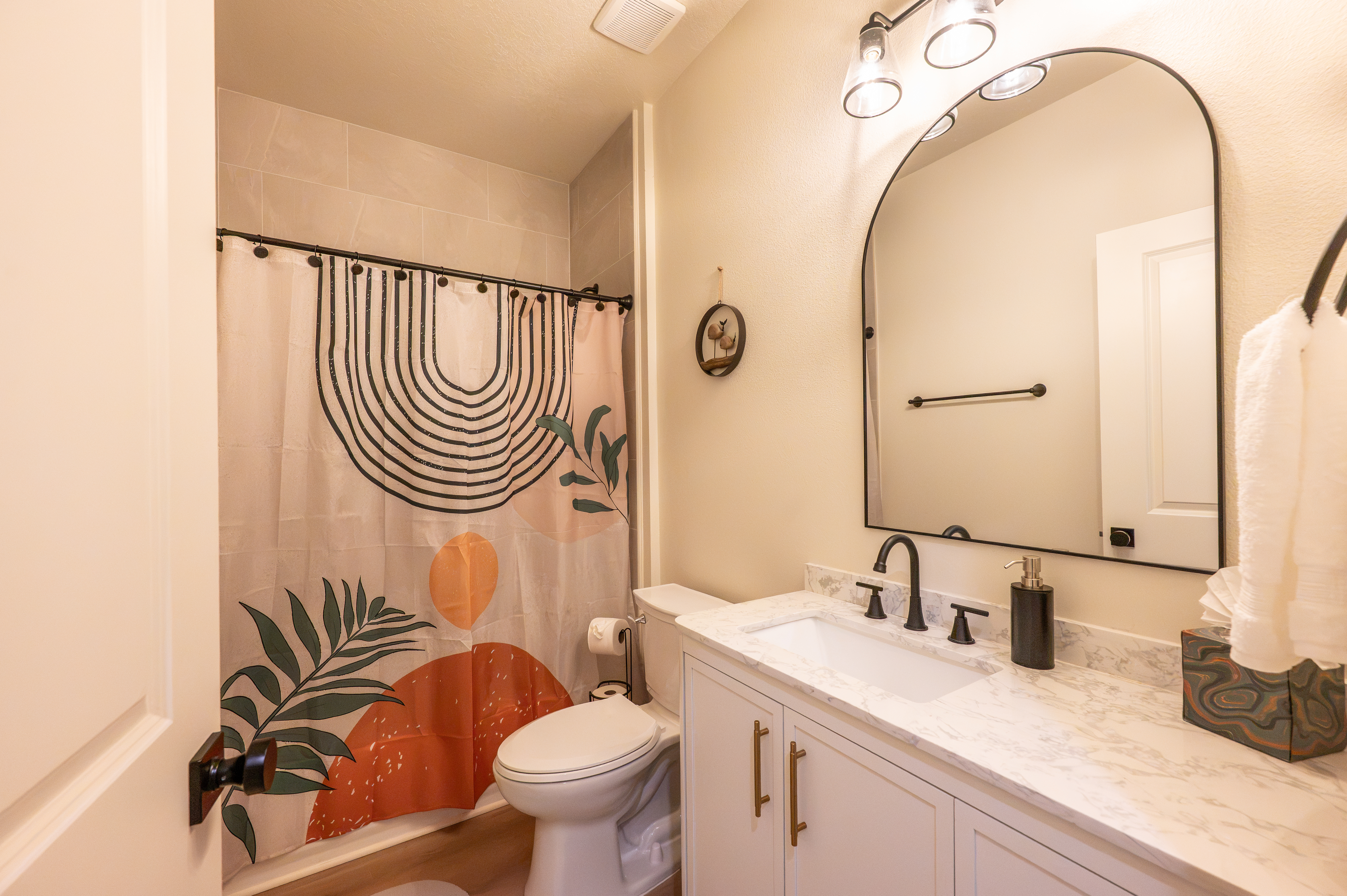 Stylish modern bathroom with marble vanity and chic arched mirror
