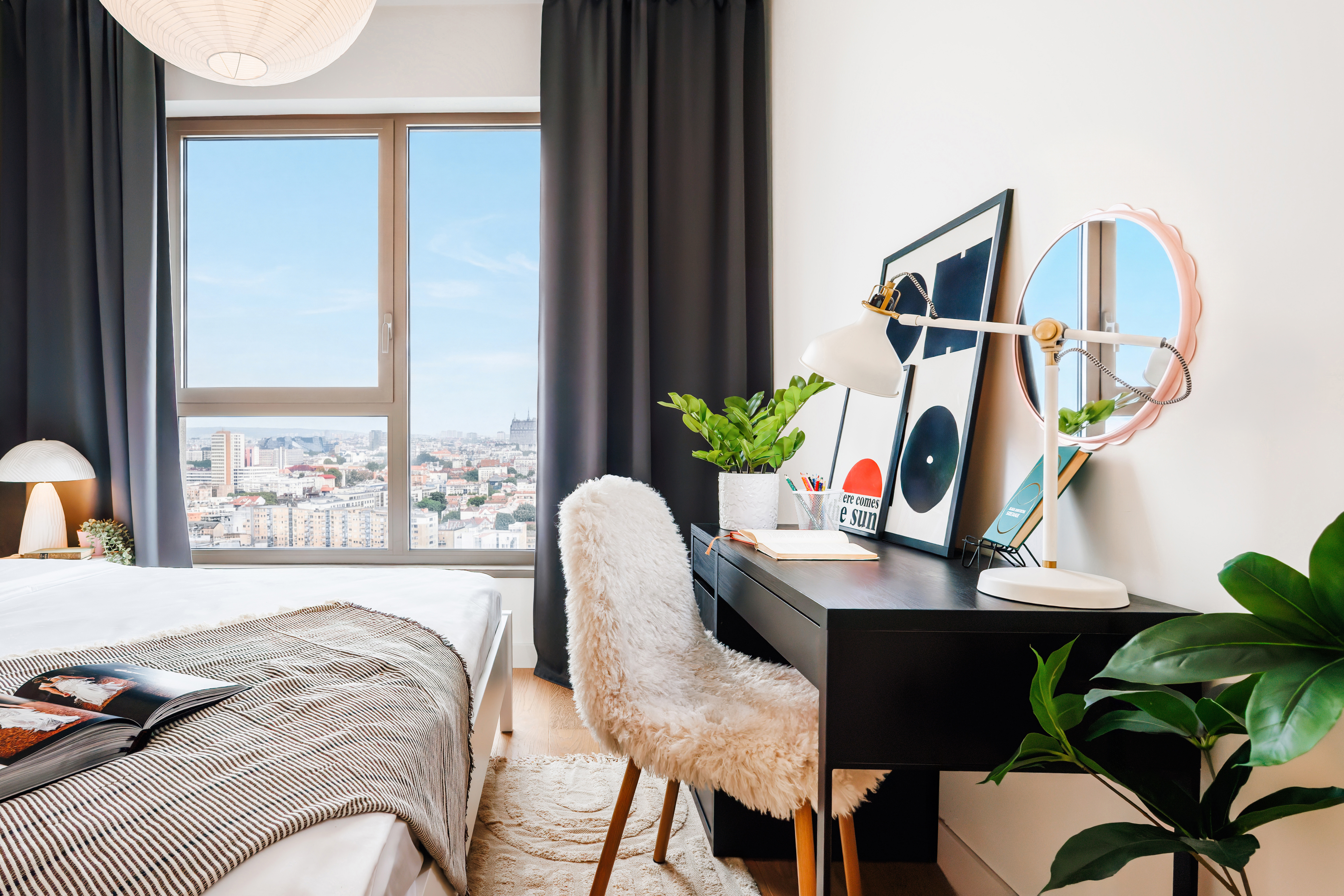 Bright bedroom with city views, cozy workspace, and modern decor