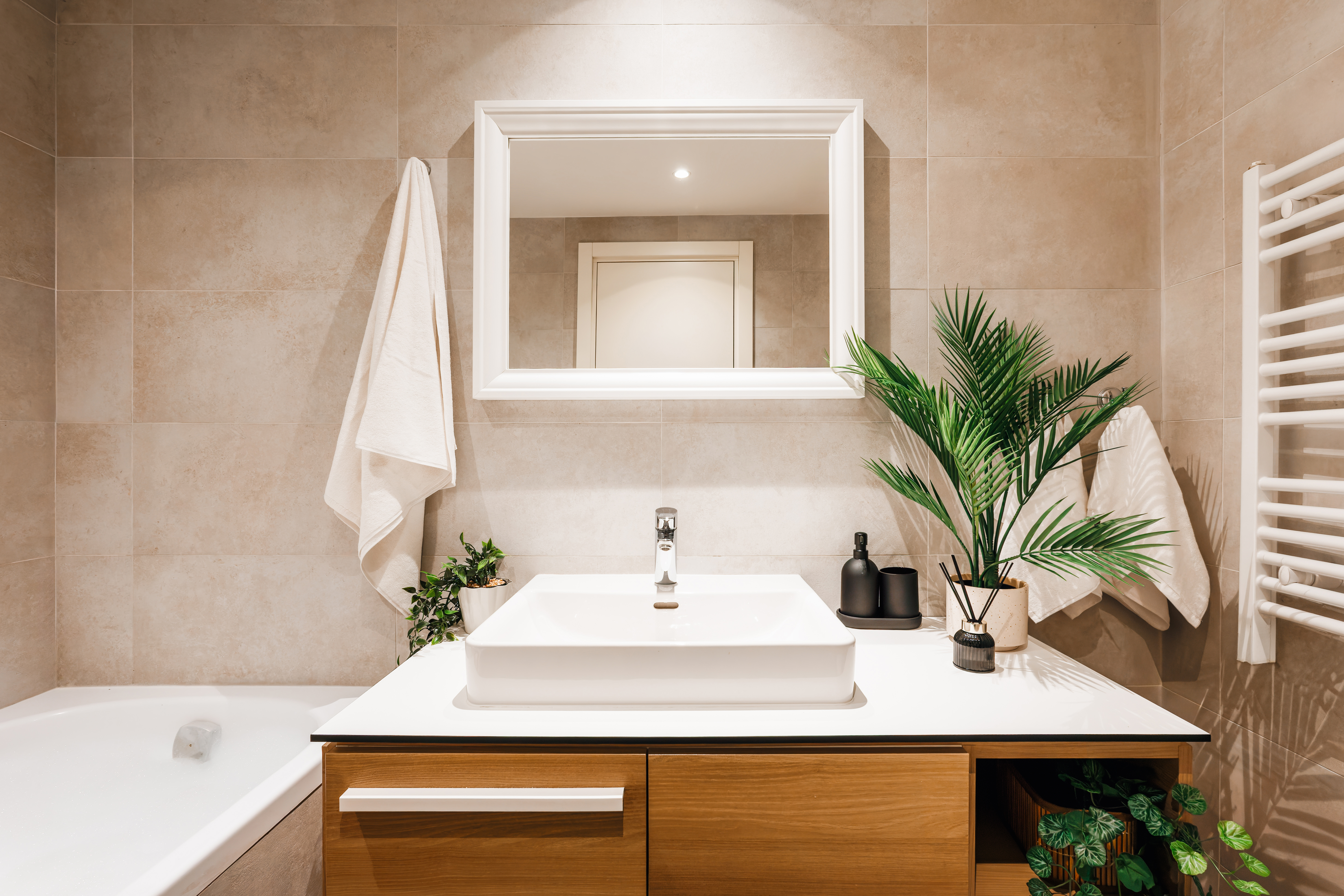 Modern spa-style bathroom with sleek vanity, tub, and warm designer touches