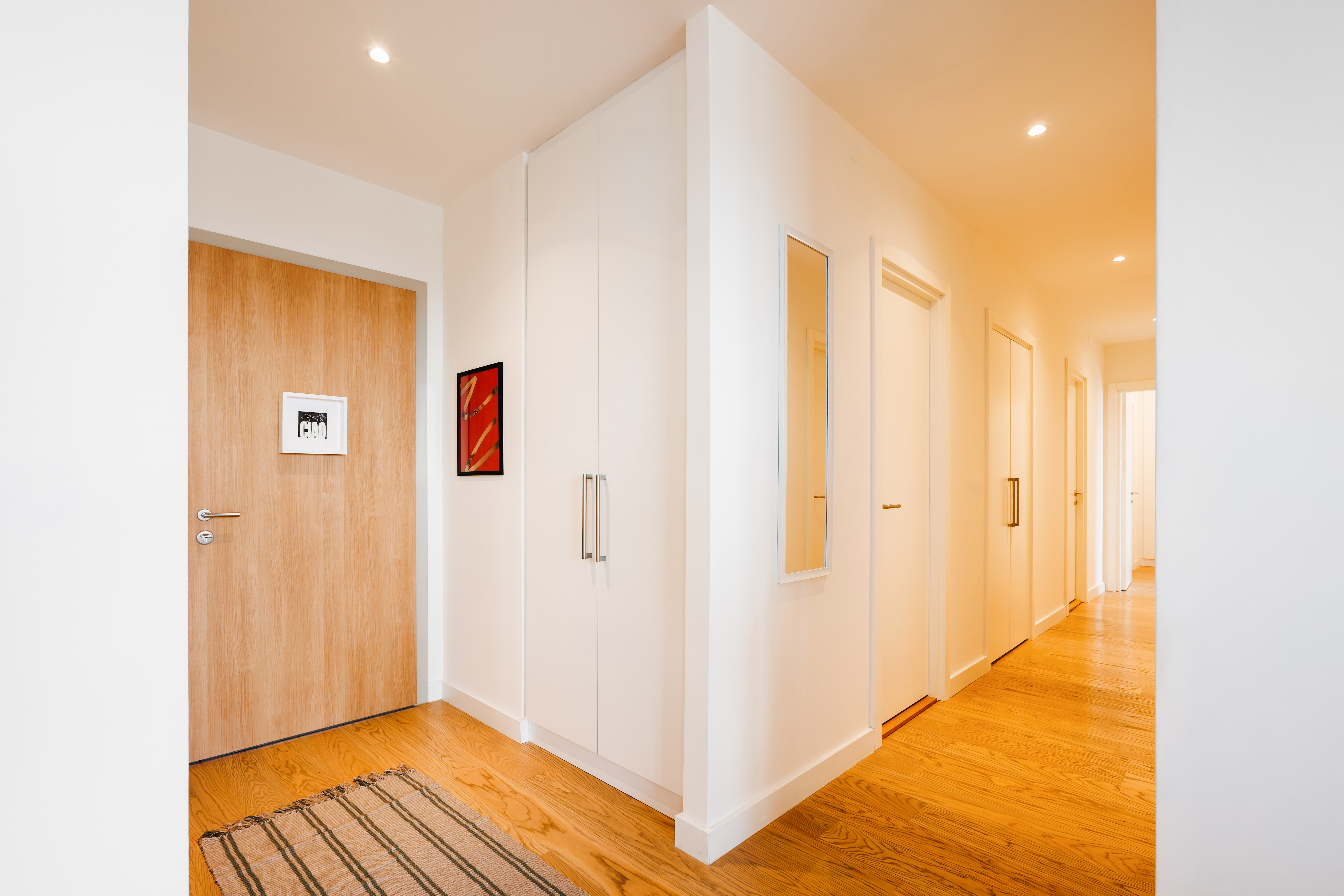 Bright modern hallway with warm wood floors and sleek built-in storage