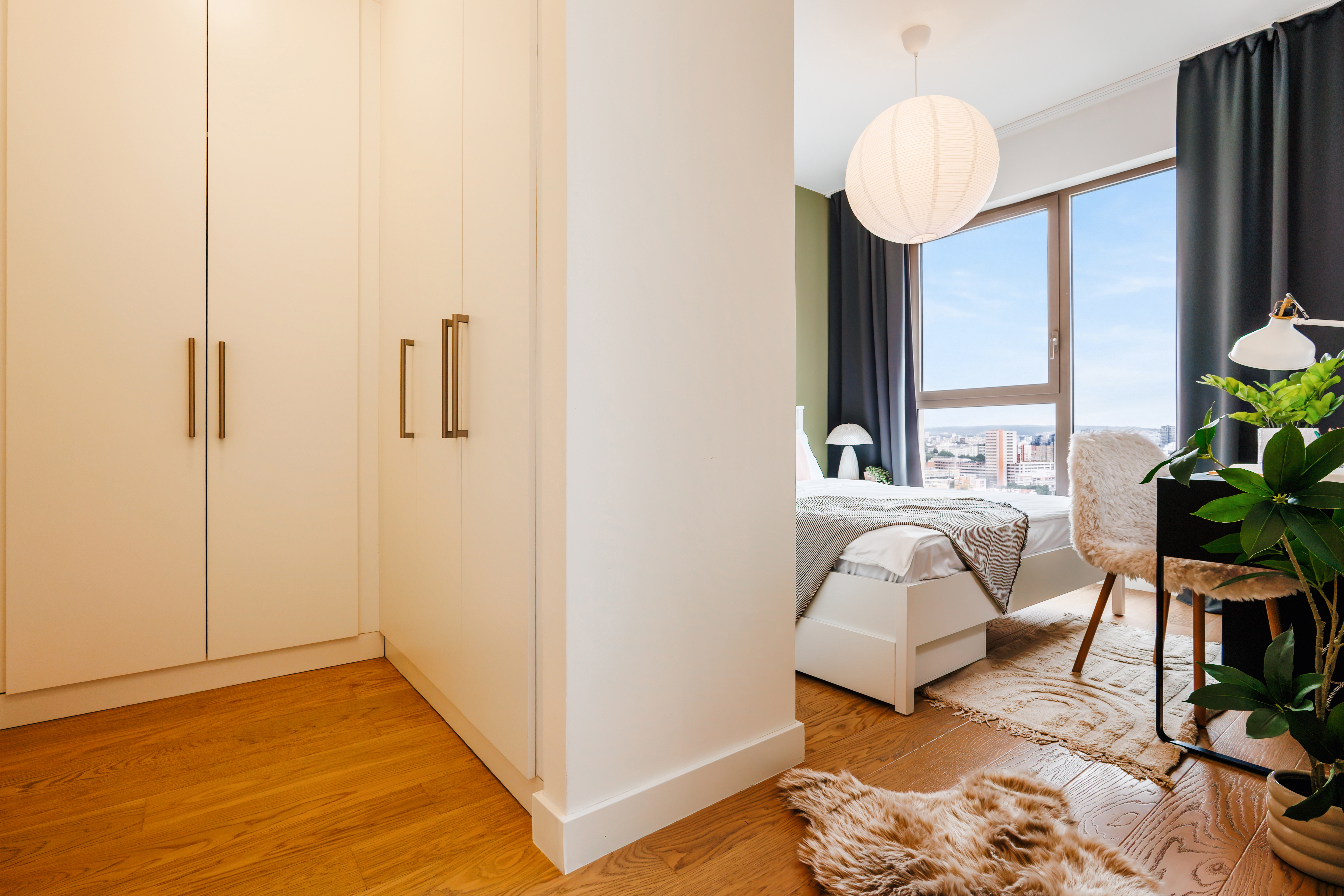 Cozy modern bedroom with large wardrobe, desk, and city-view window