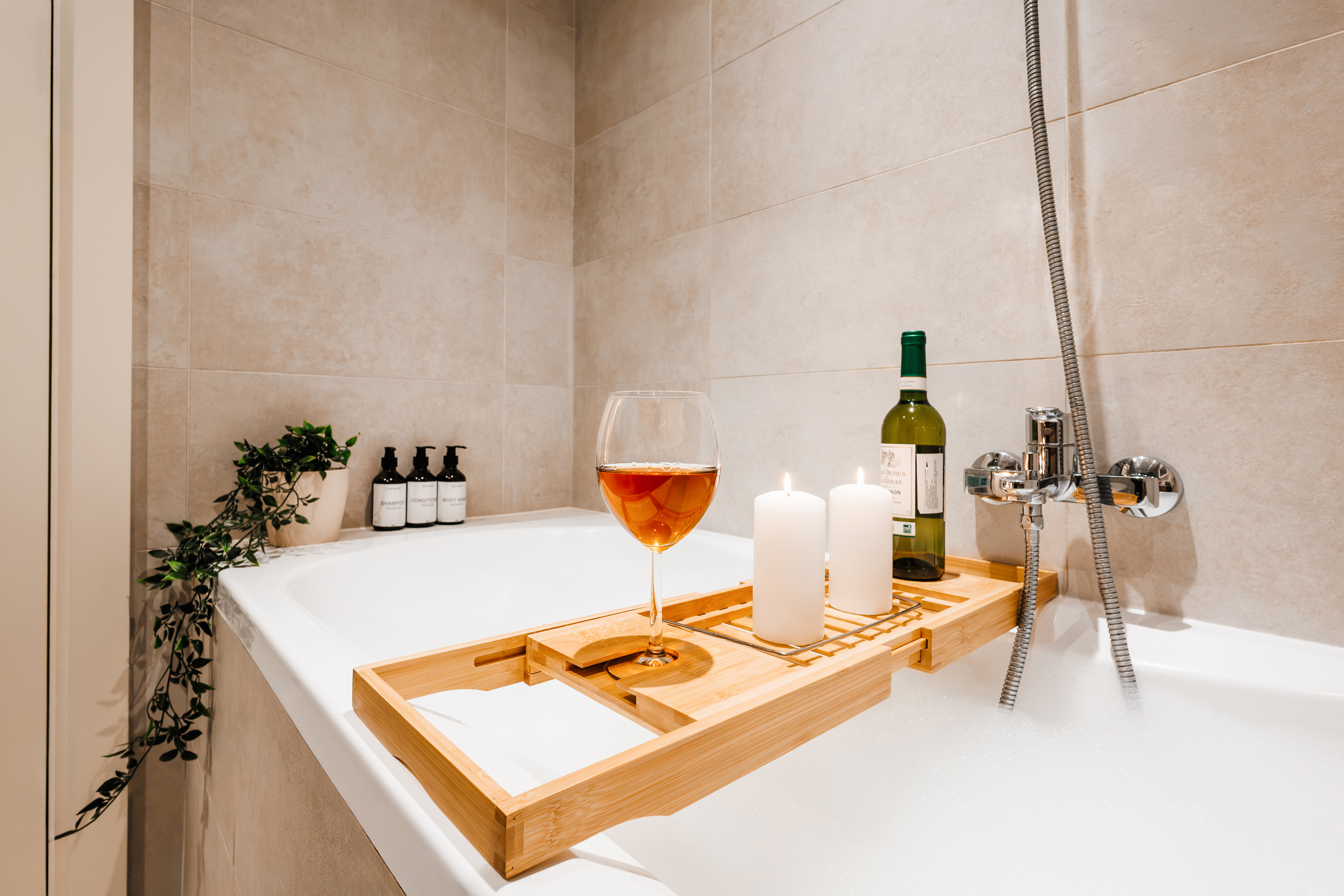 Spa-like soaking tub with candles, wine, and a serene modern design