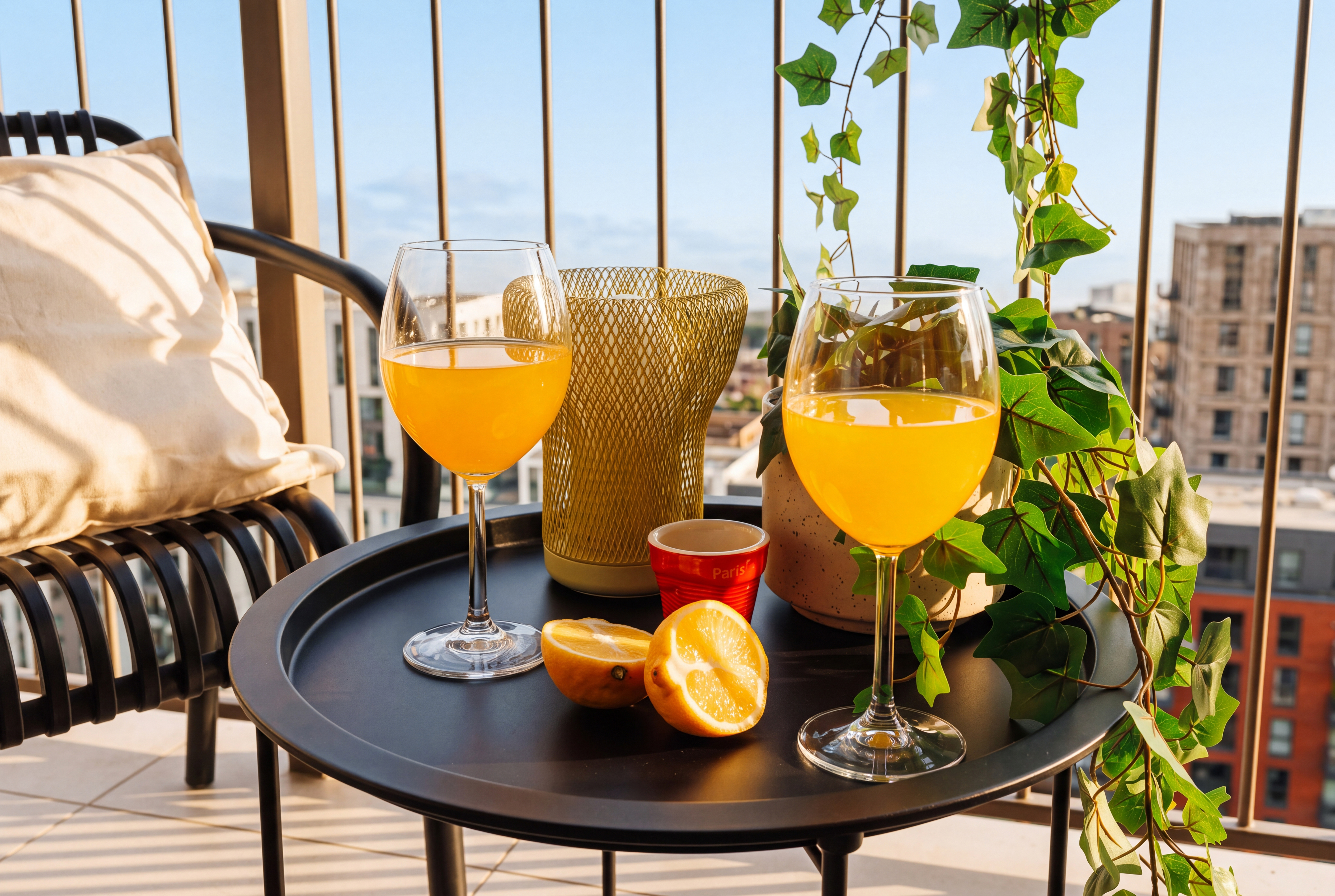 Sunny city-view balcony with cozy seating and refreshing drinks