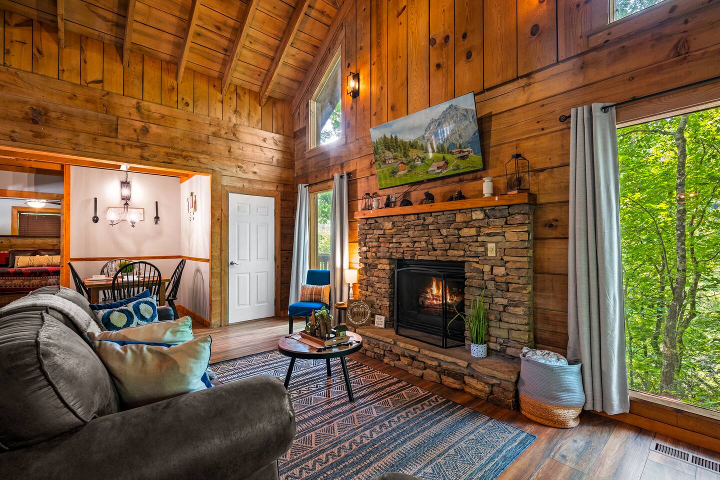 Relax in our cozy living room featuring a stone fireplace and scenic forest views – the perfect spot for chilly evenings or quality time with family