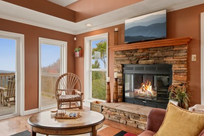 The stone fireplace in the living room runs on propane with a timer, so there's no wood to haul and no ash to clean. A twig chair, a round side table and windows on both sides of the hearth make this corner where people tend to settle in.