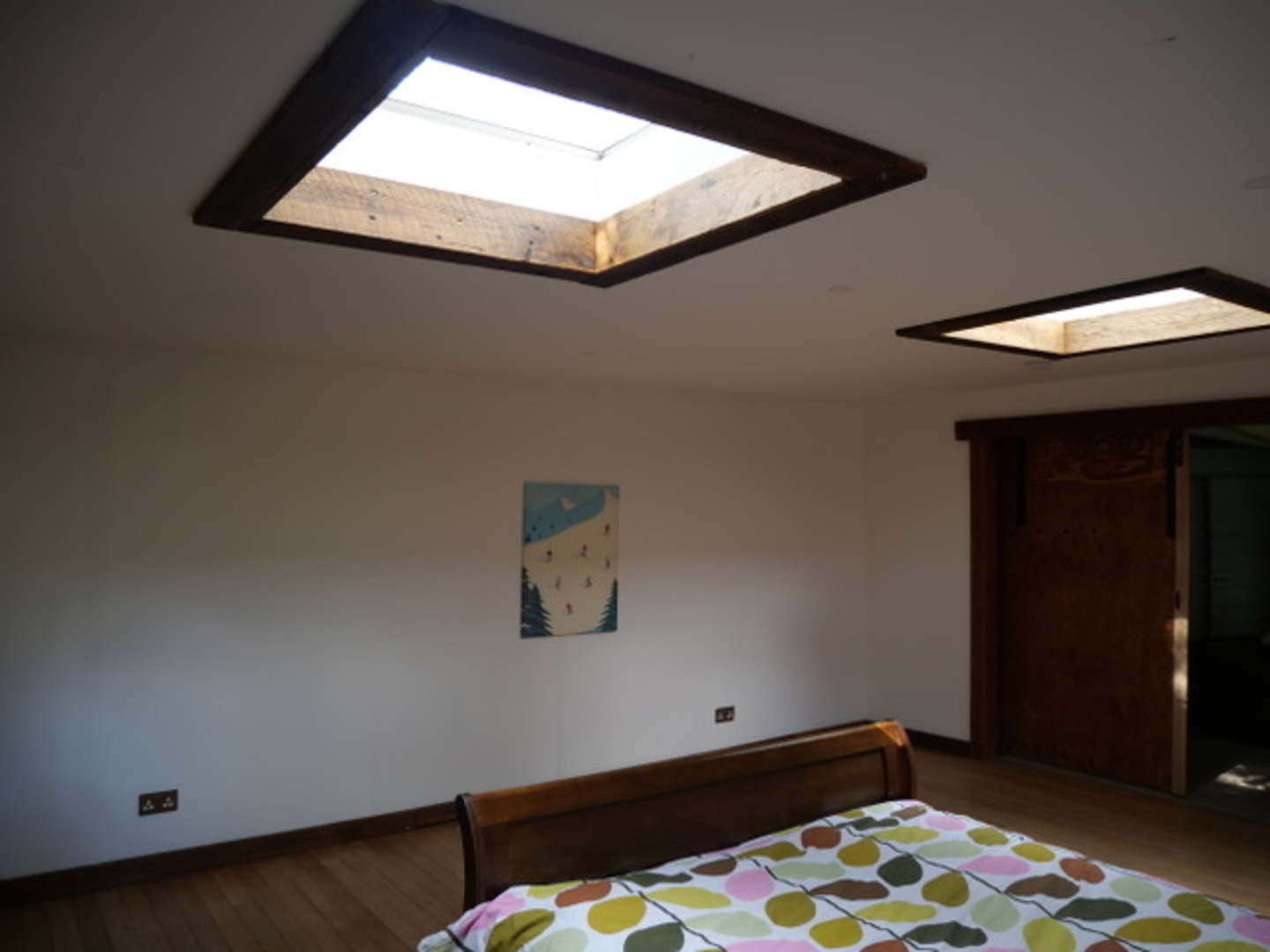 Bright skylit bedroom with warm wood details and airy, spacious feel