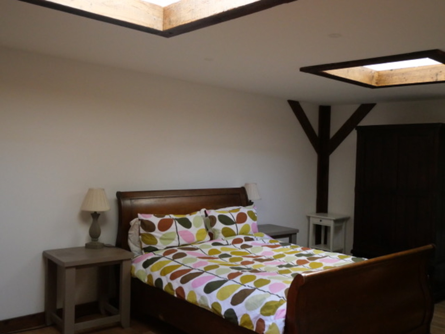 Cozy skylit bedroom with wooden accents and colorful bedding