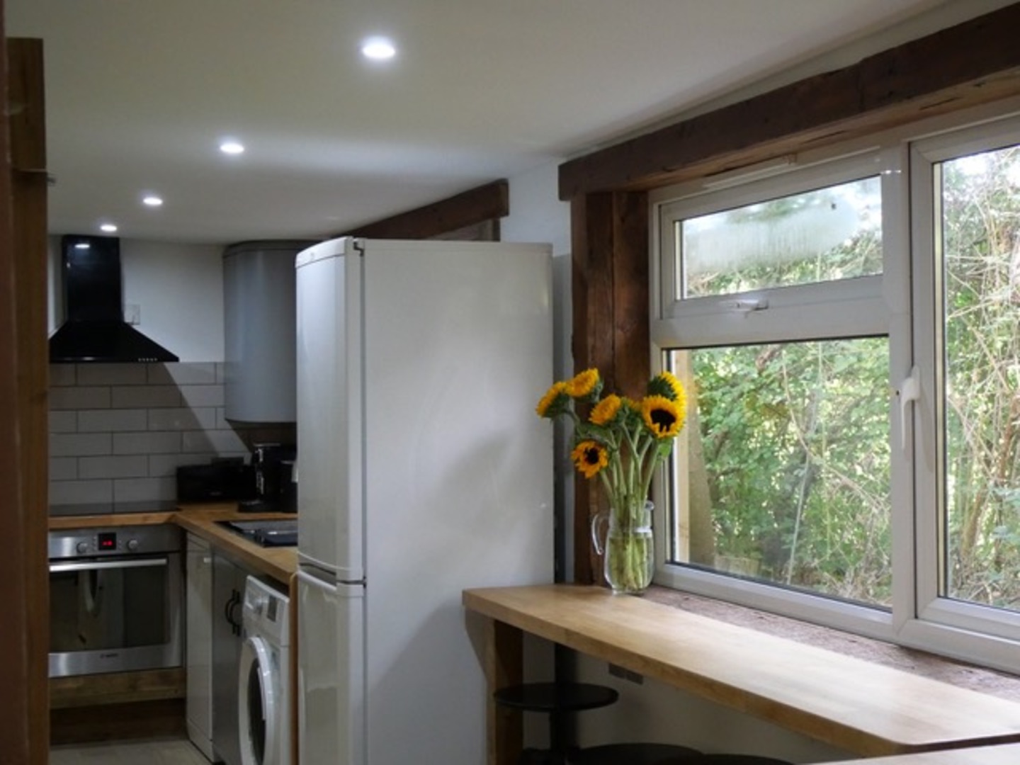 Bright modern kitchen with leafy views and a cozy breakfast bar