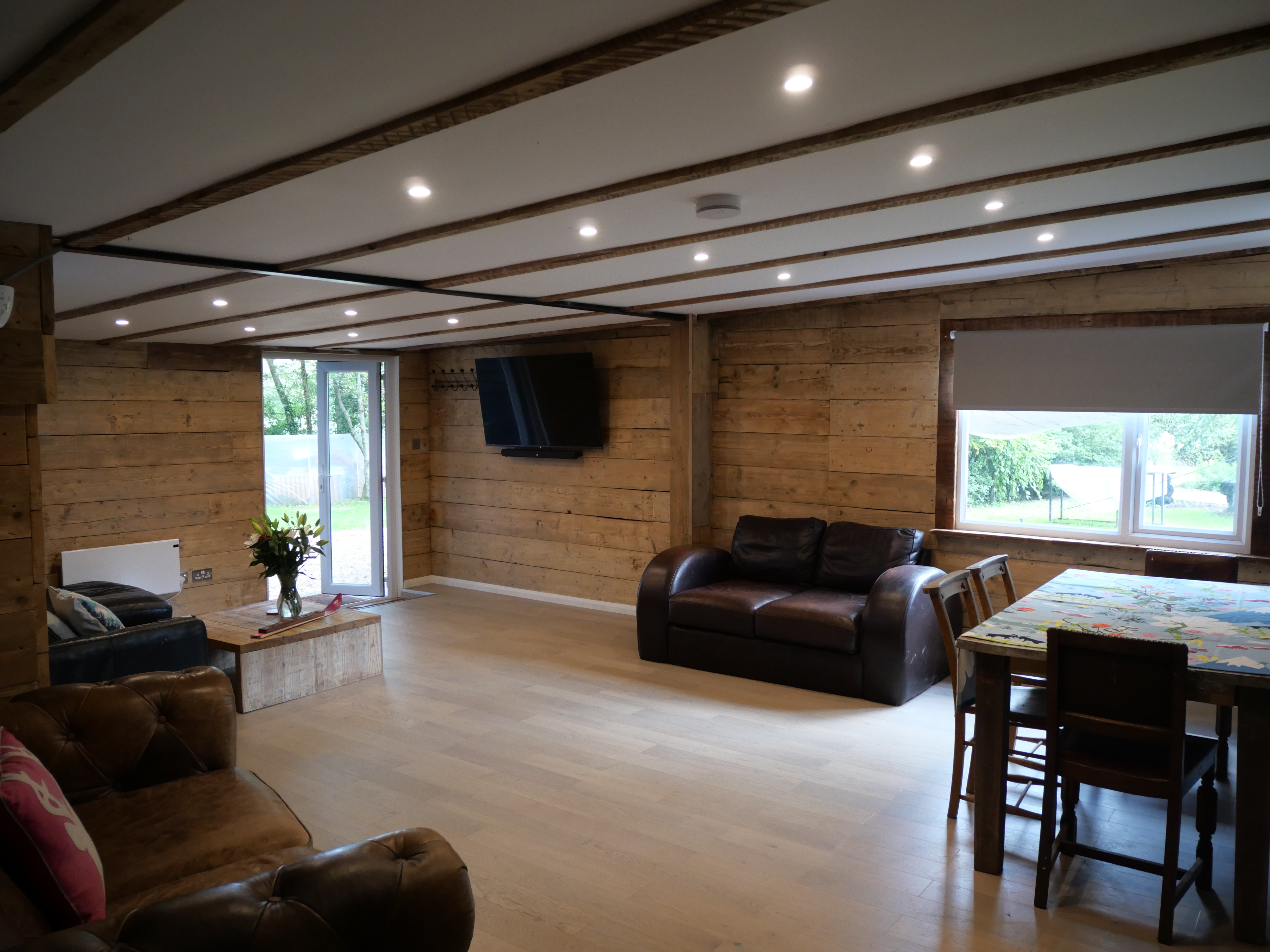 Spacious rustic lounge with dining area, TV, and garden access