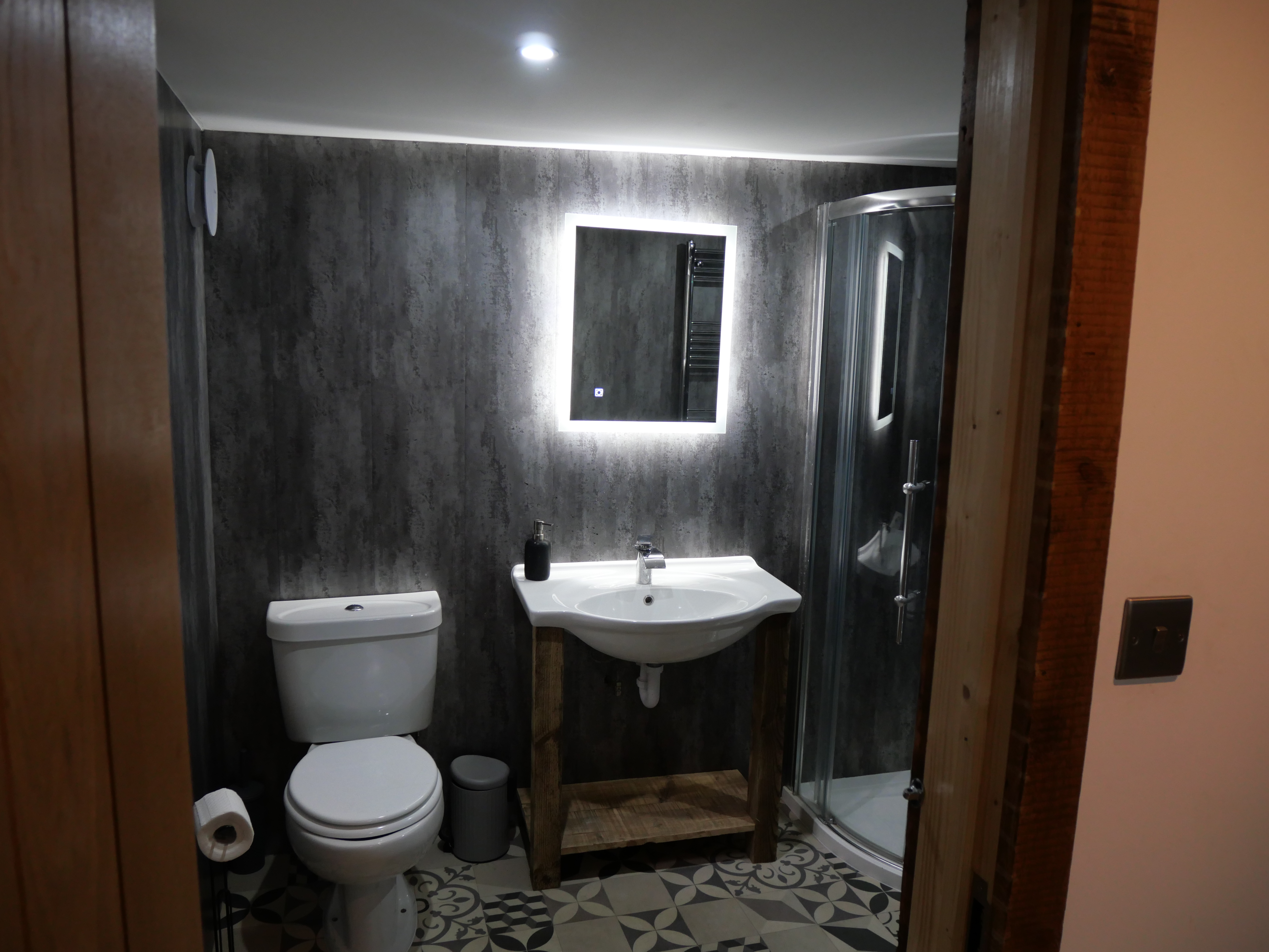 Modern bathroom with LED mirror, stylish tile floor, and walk-in shower