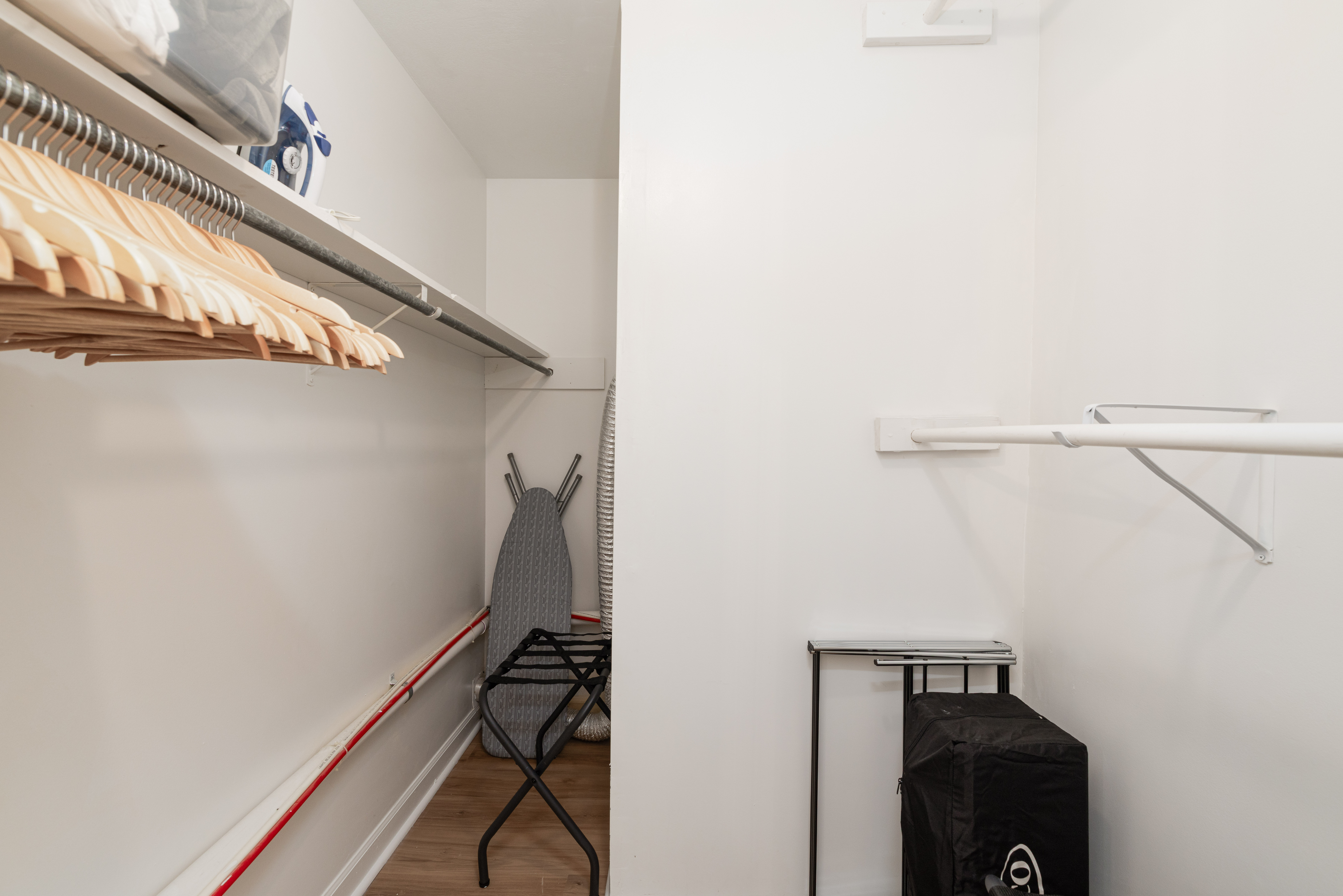 Main House closet with hangers, an ironing board and a luggage rack