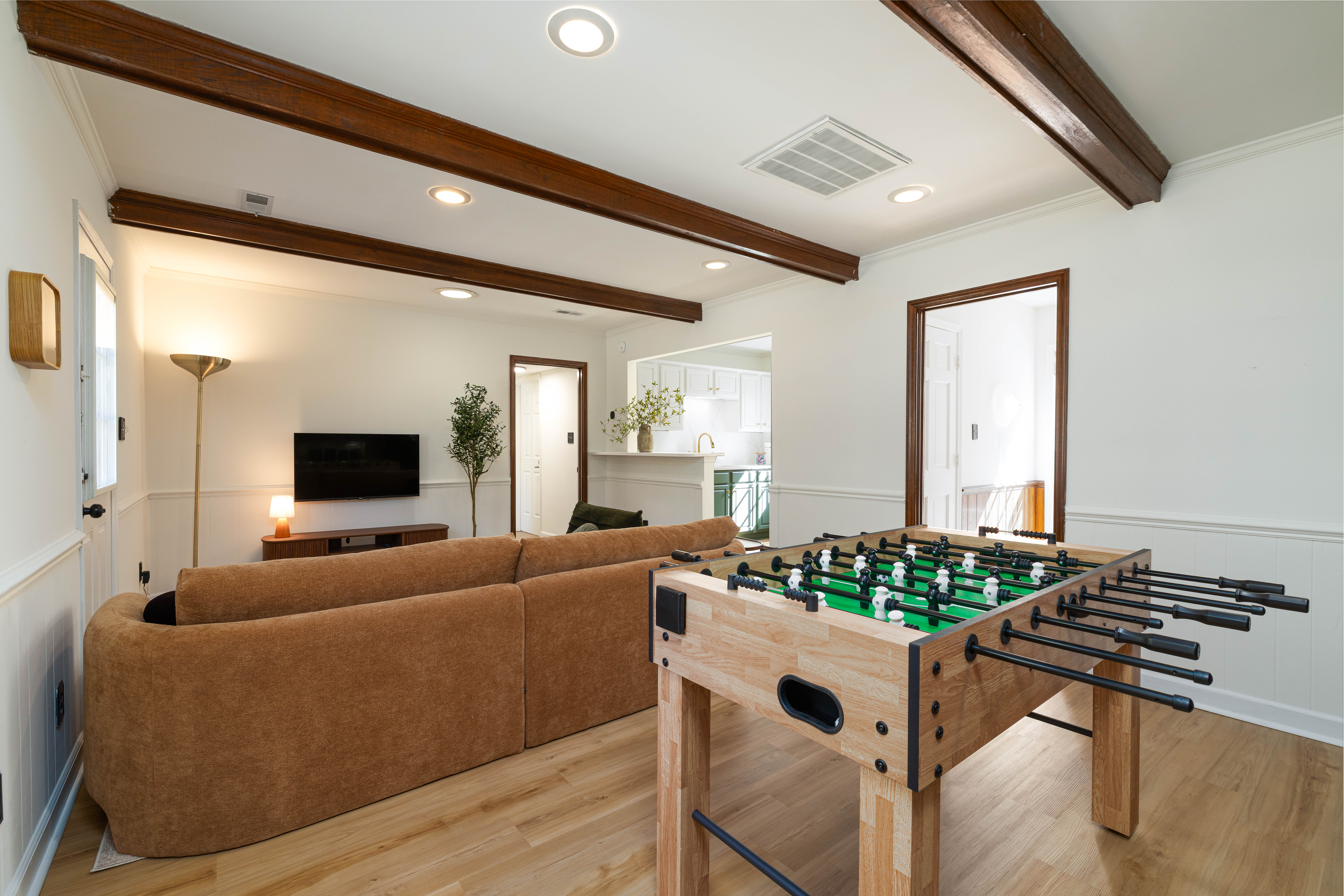 Main House family room with a sectional, foosball table and beamed ceiling