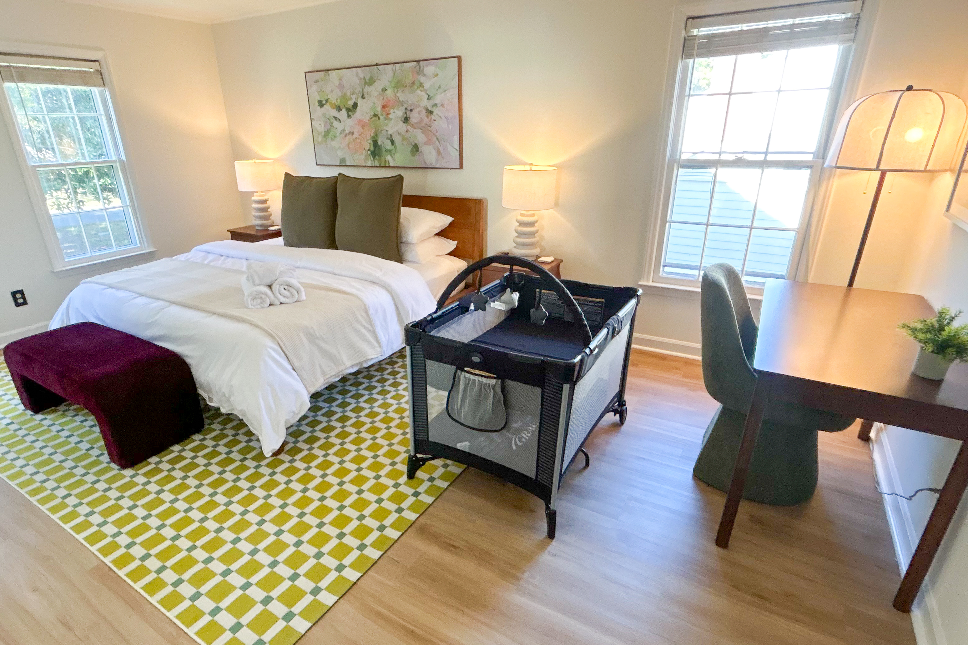 Bright family-friendly bedroom with workspace and baby crib