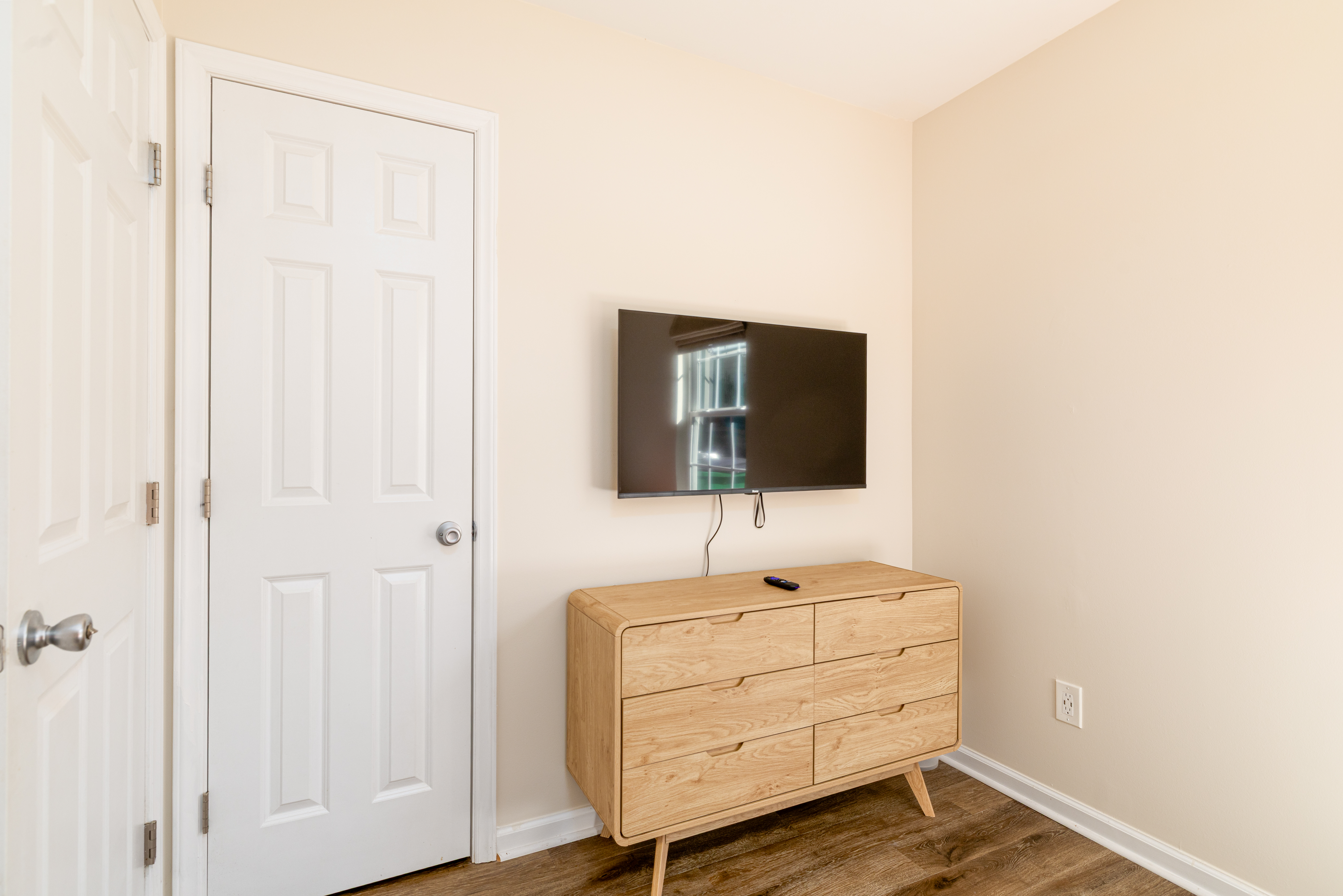 Minimalist room with wall-mounted TV and stylish wood dresser