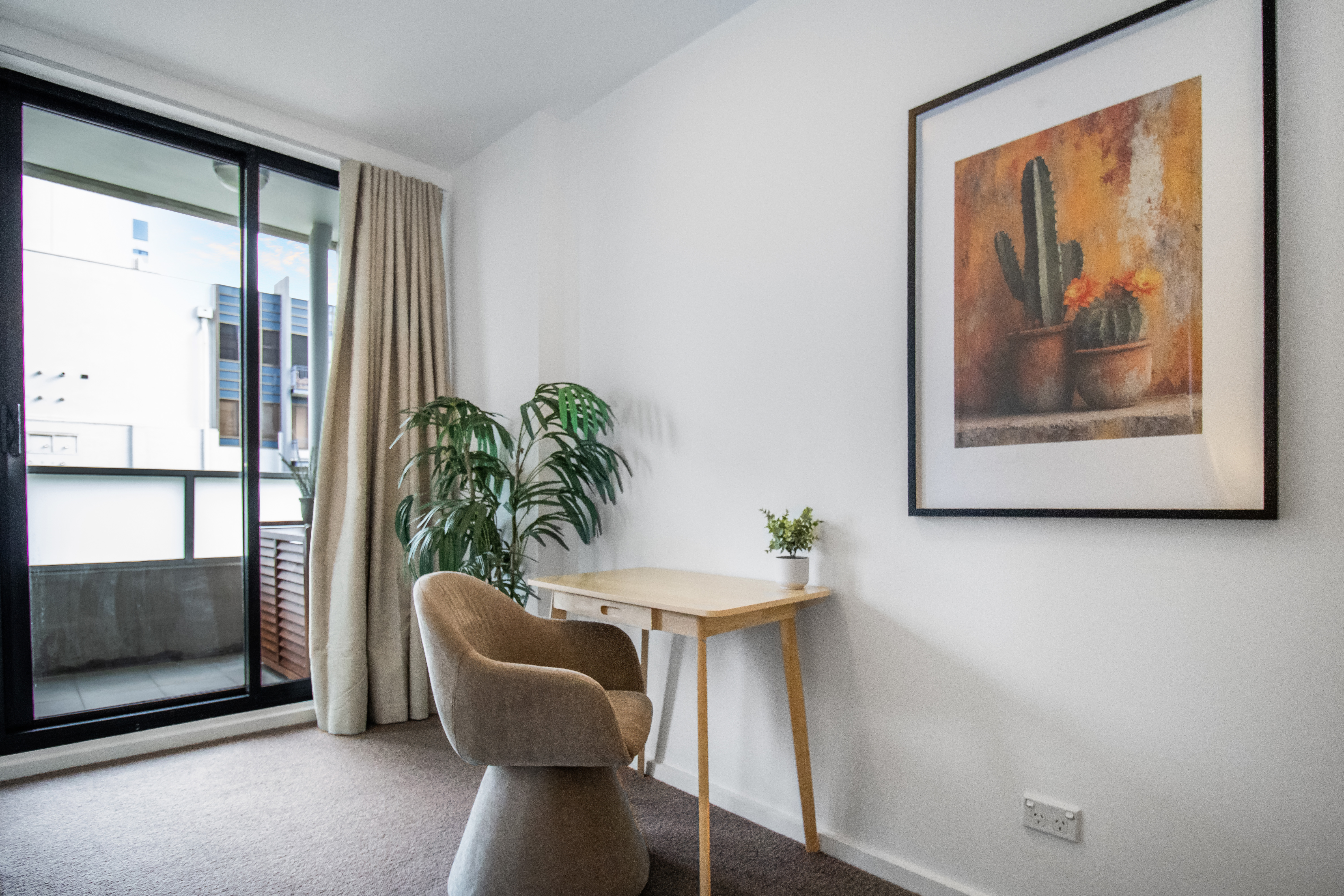 Bright balcony-side reading nook with desk, natural light, and stylish decor