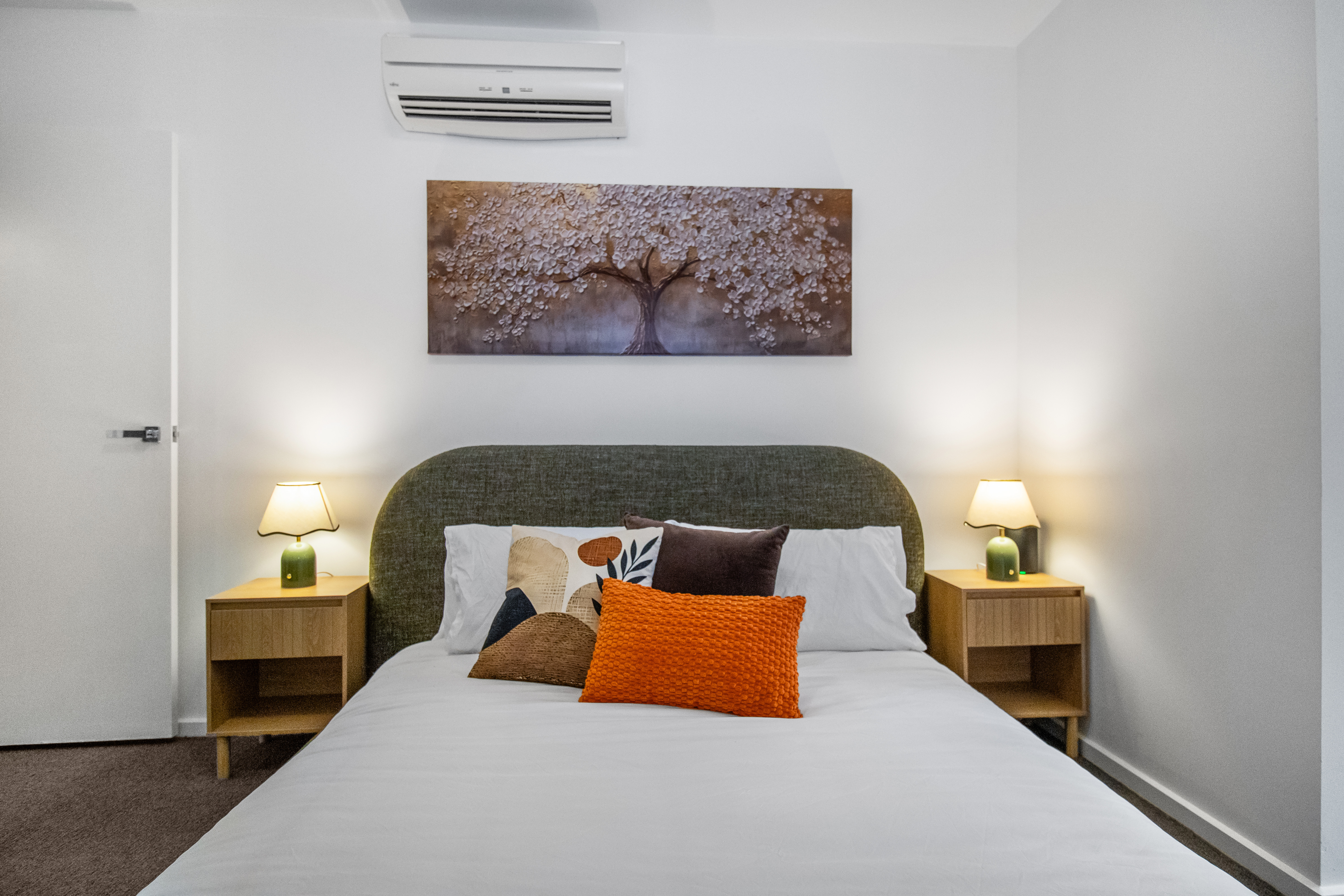 Cozy, stylish bedroom with AC, warm lighting, and inviting modern decor