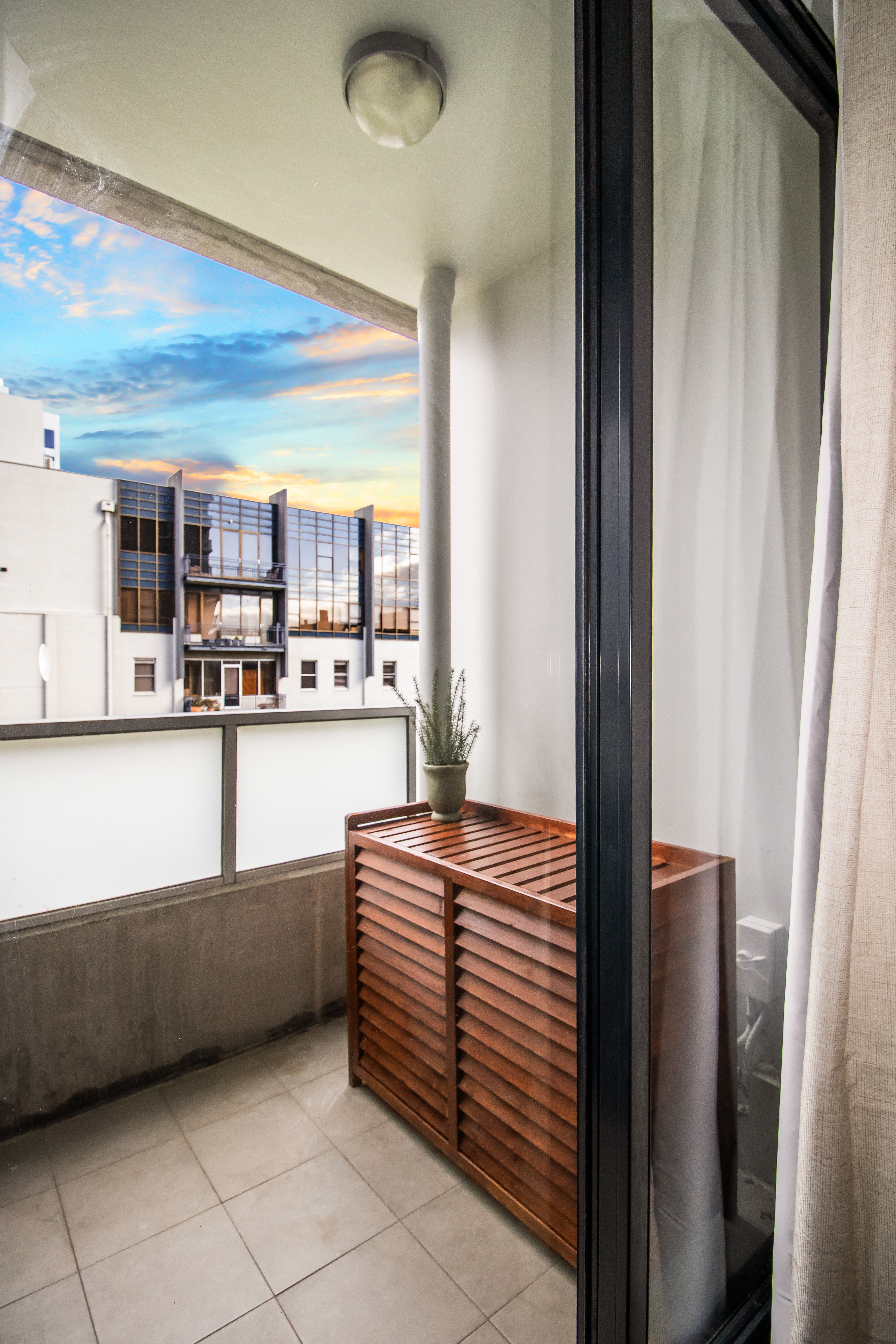 Private city-view balcony with sunset skies and stylish outdoor storage