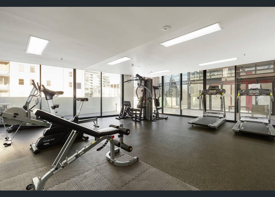 Bright on-site gym with treadmills, weights, and floor-to-ceiling windows