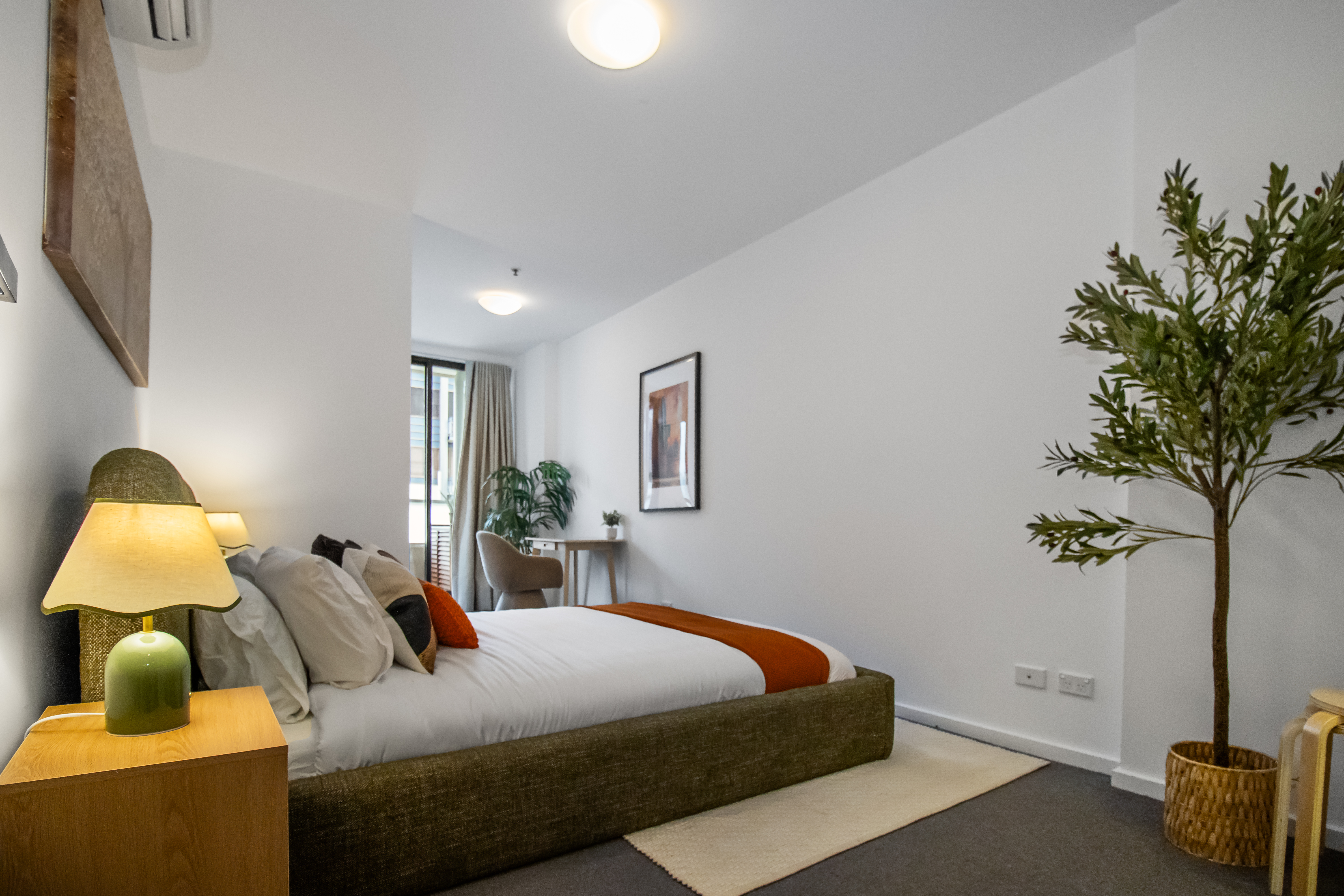 Bright, modern bedroom with plush bedding, desk nook, and natural light