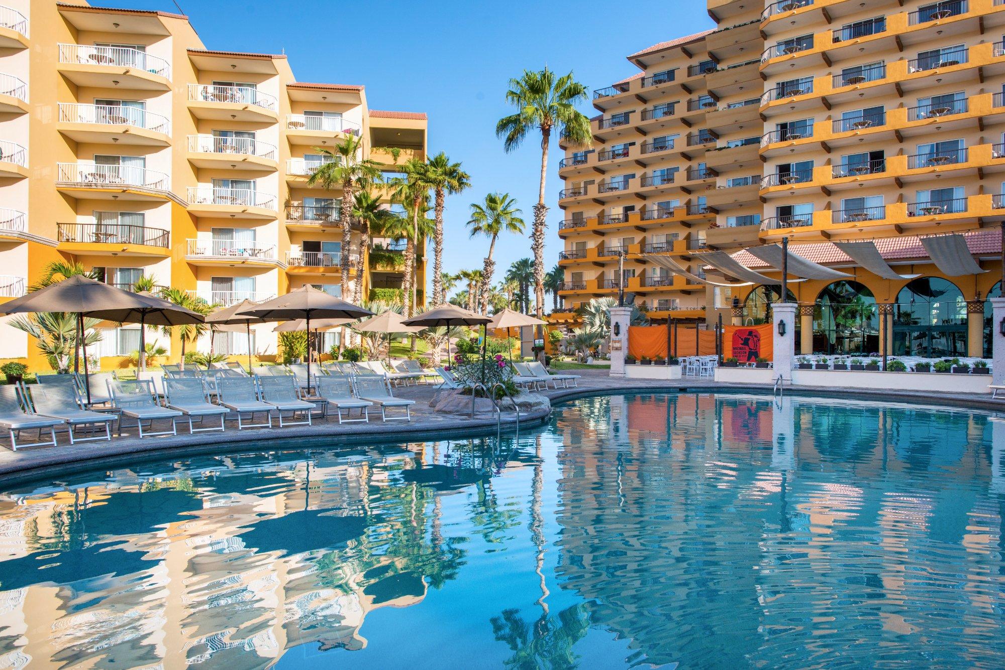 Resort-style pool oasis with loungers, palms, and sunny condo views
