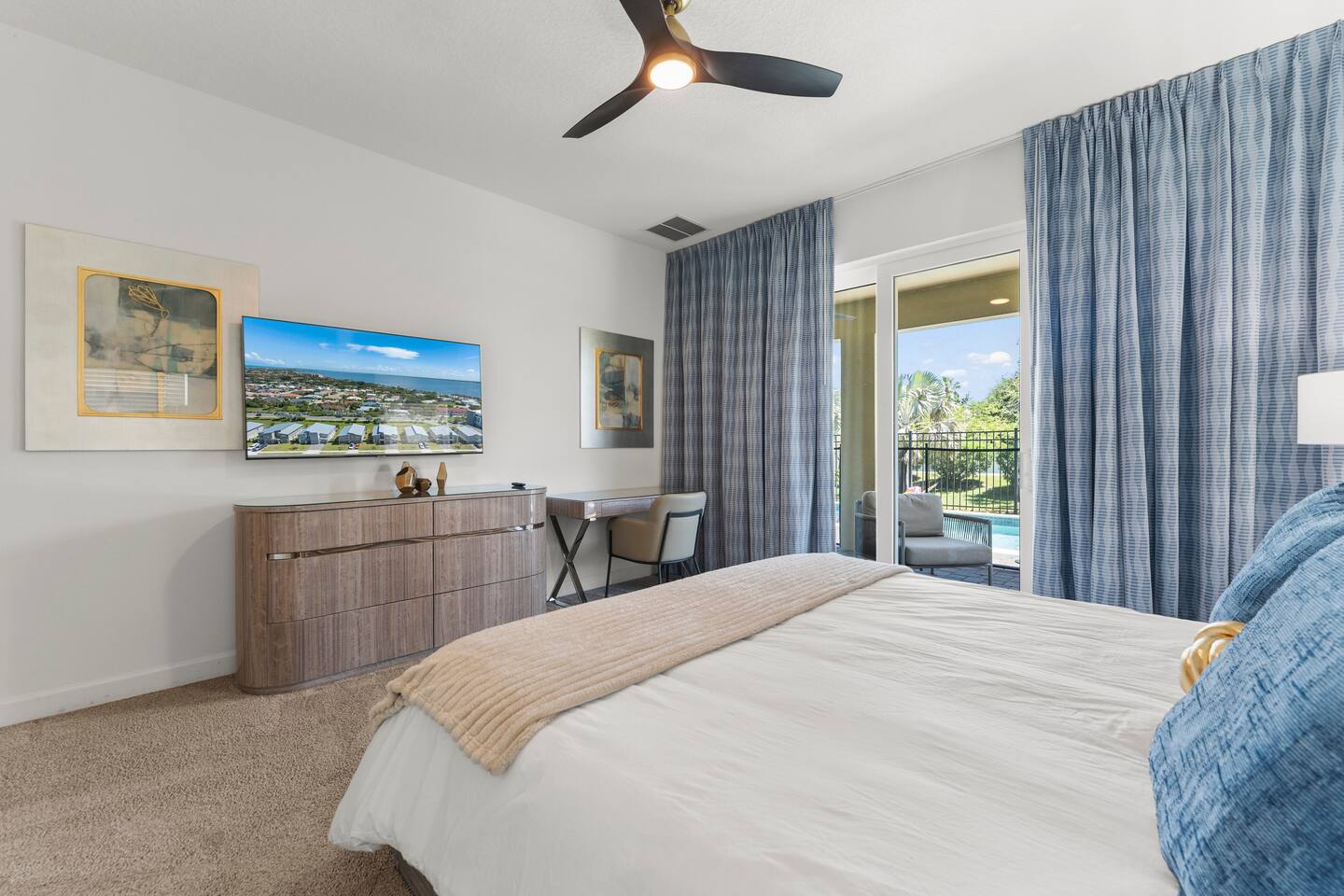 Bright bedroom with TV, workspace, and private balcony access