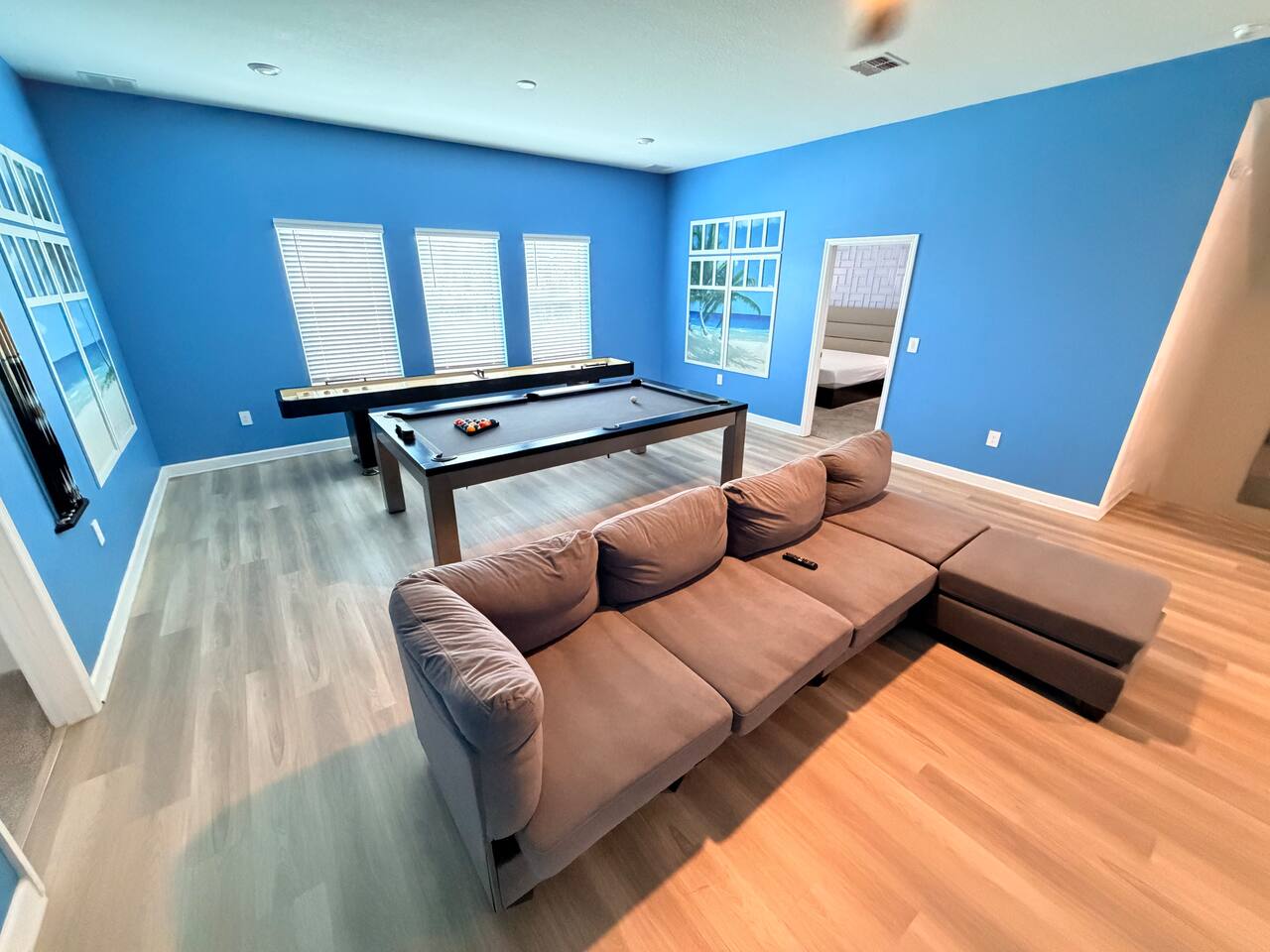 Spacious game room with pool table, shuffleboard, and cozy sectional