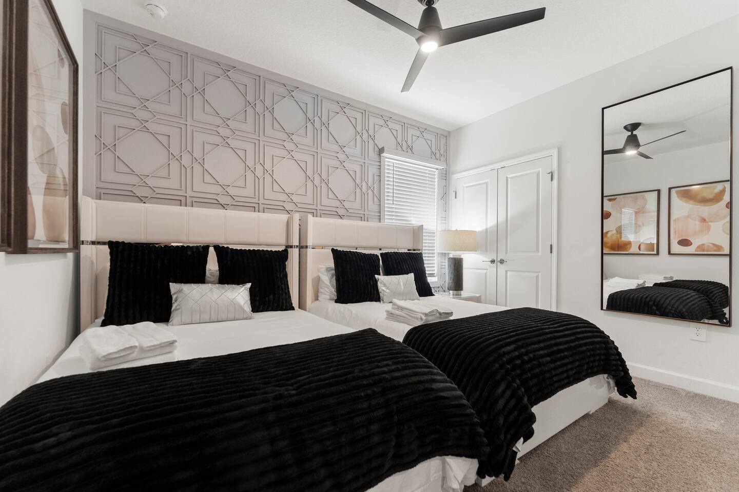 Chic double-bedroom with accent wall, ceiling fan, and stylish decor