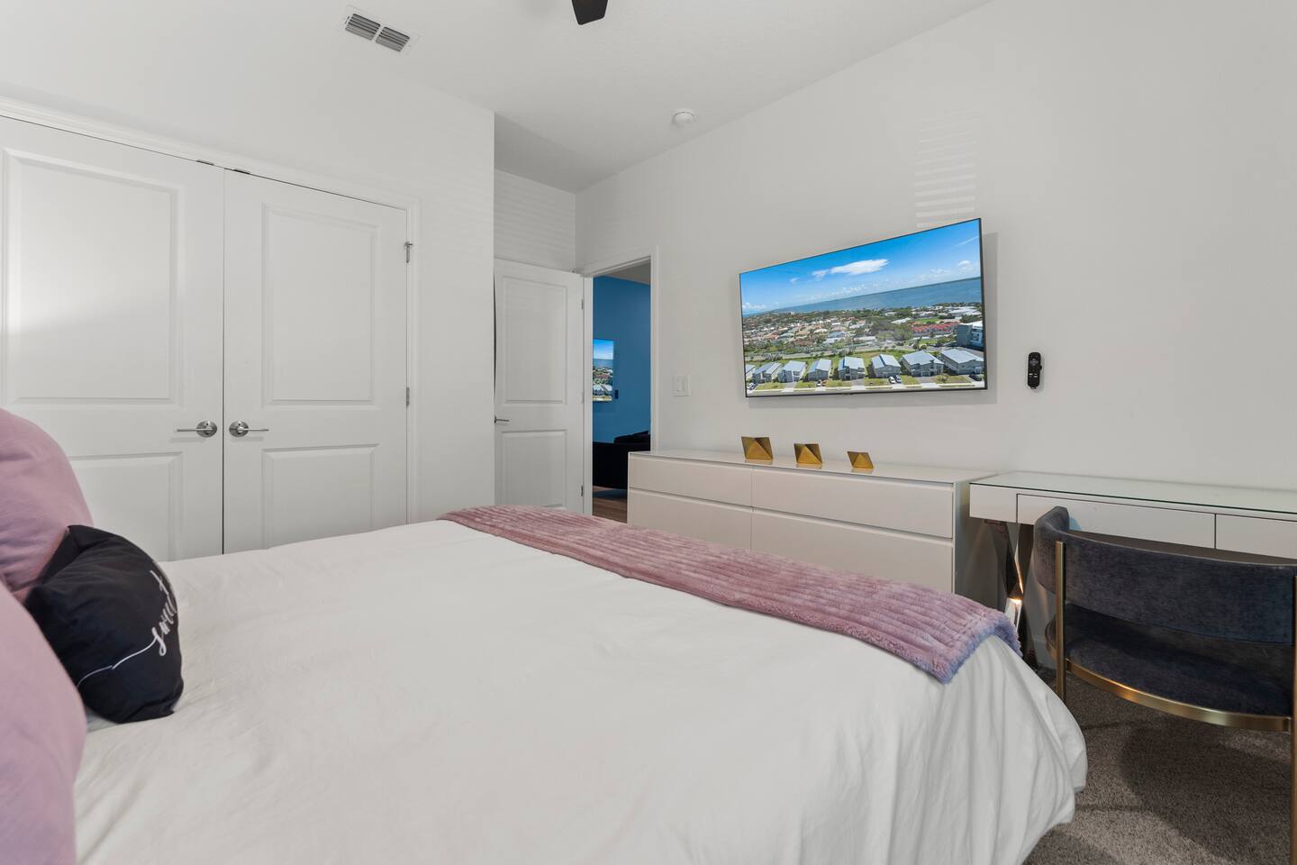 Bright modern bedroom with wall-mounted TV and sleek vanity area