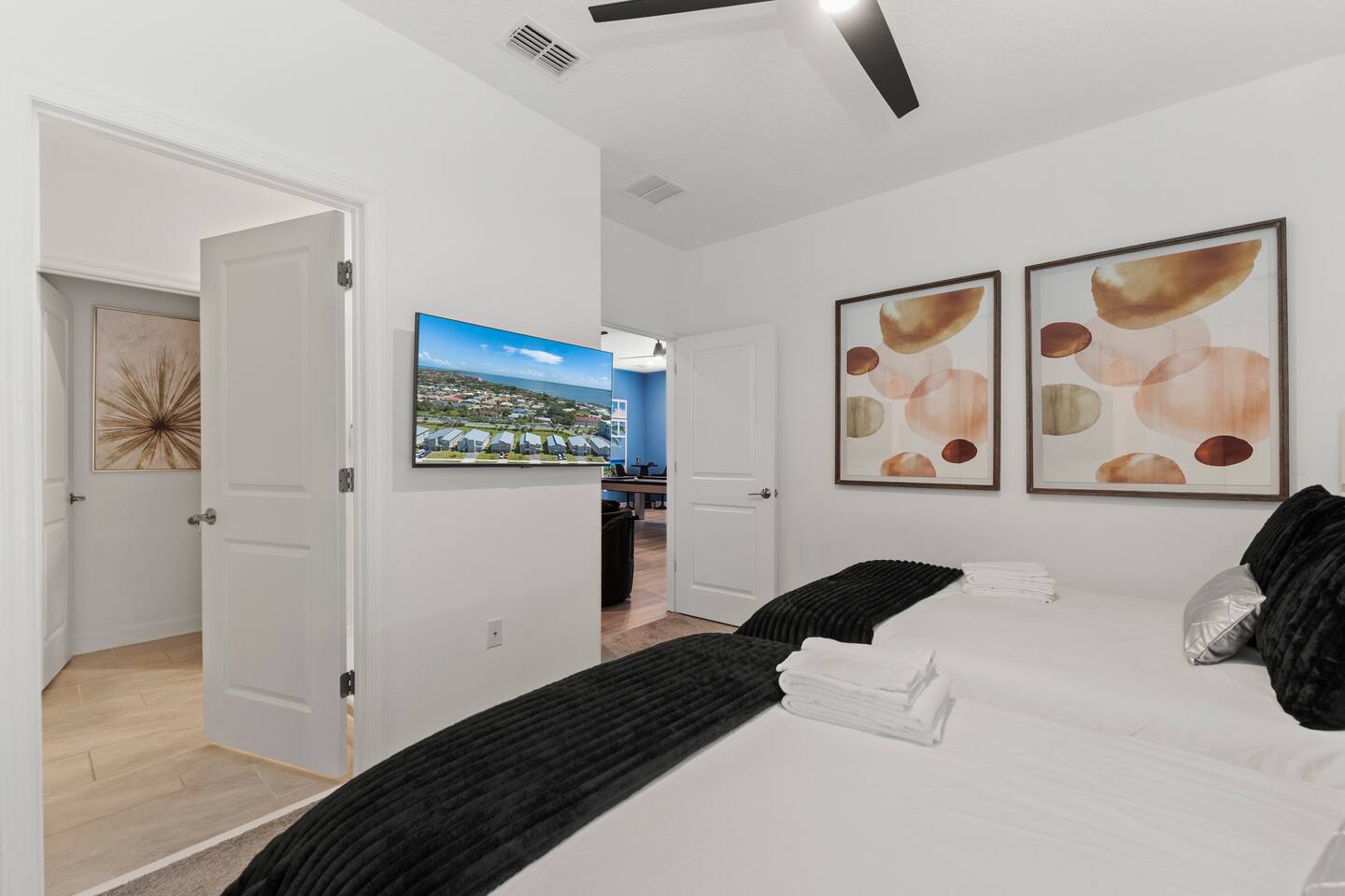 Bright modern bedroom with two beds, wall-mounted TV, and stylish decor