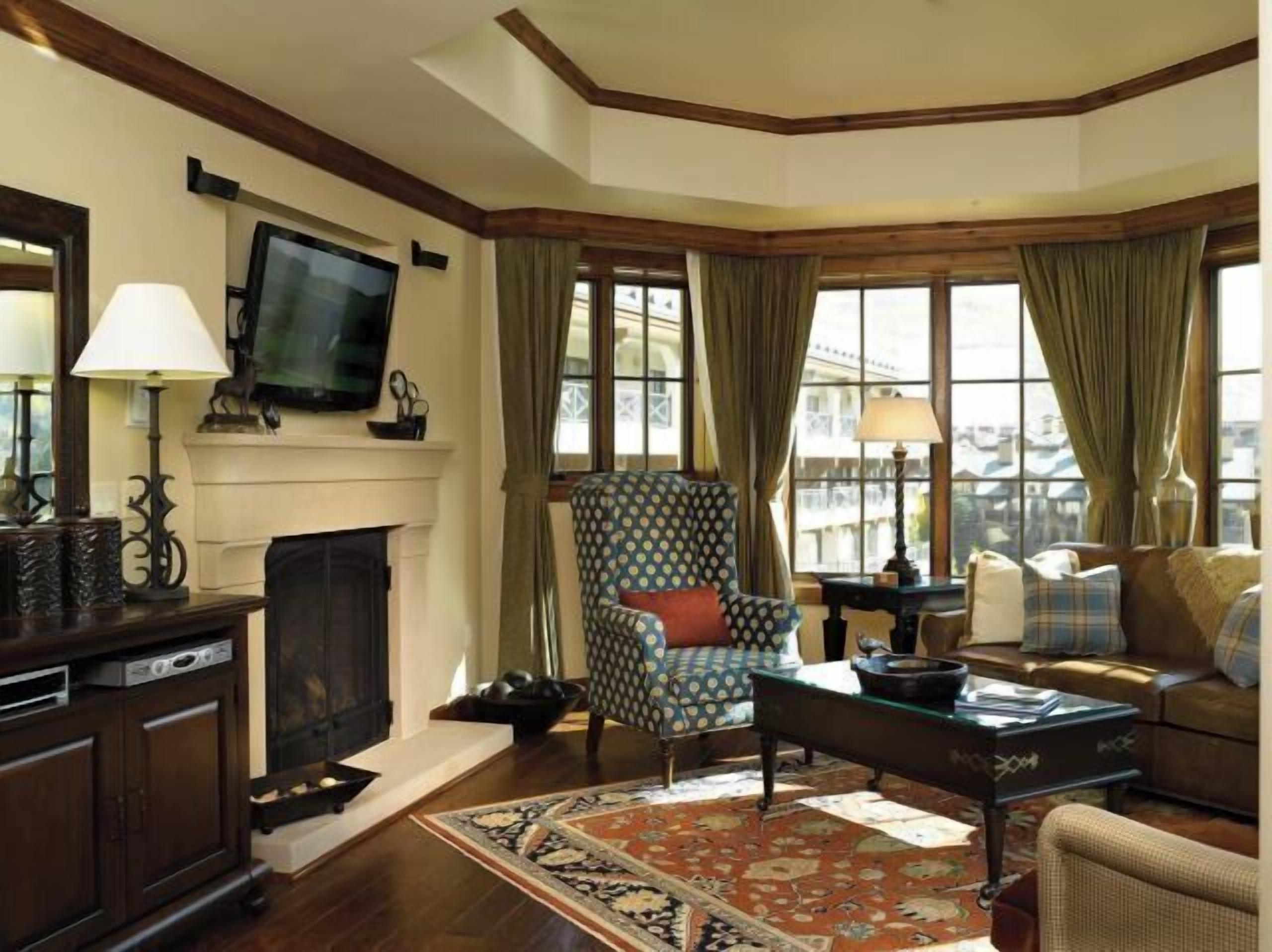 Cozy upscale living room with fireplace, TV, and sunlit window seating