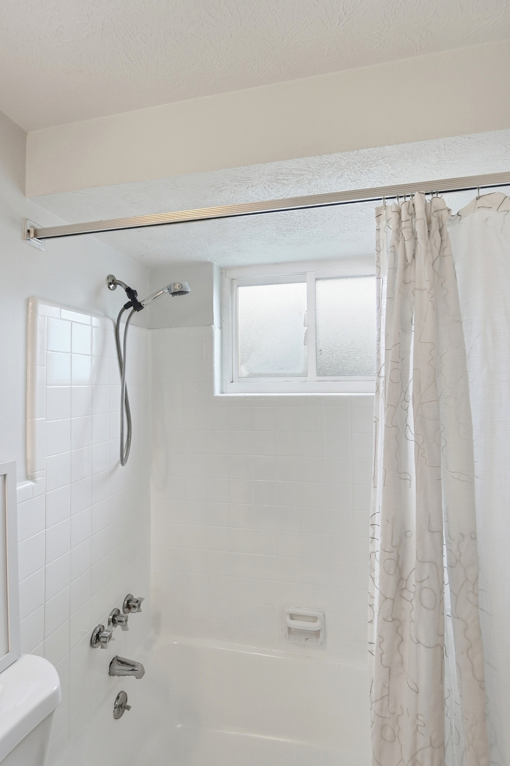 Bright bathroom with tub-shower combo and frosted natural light