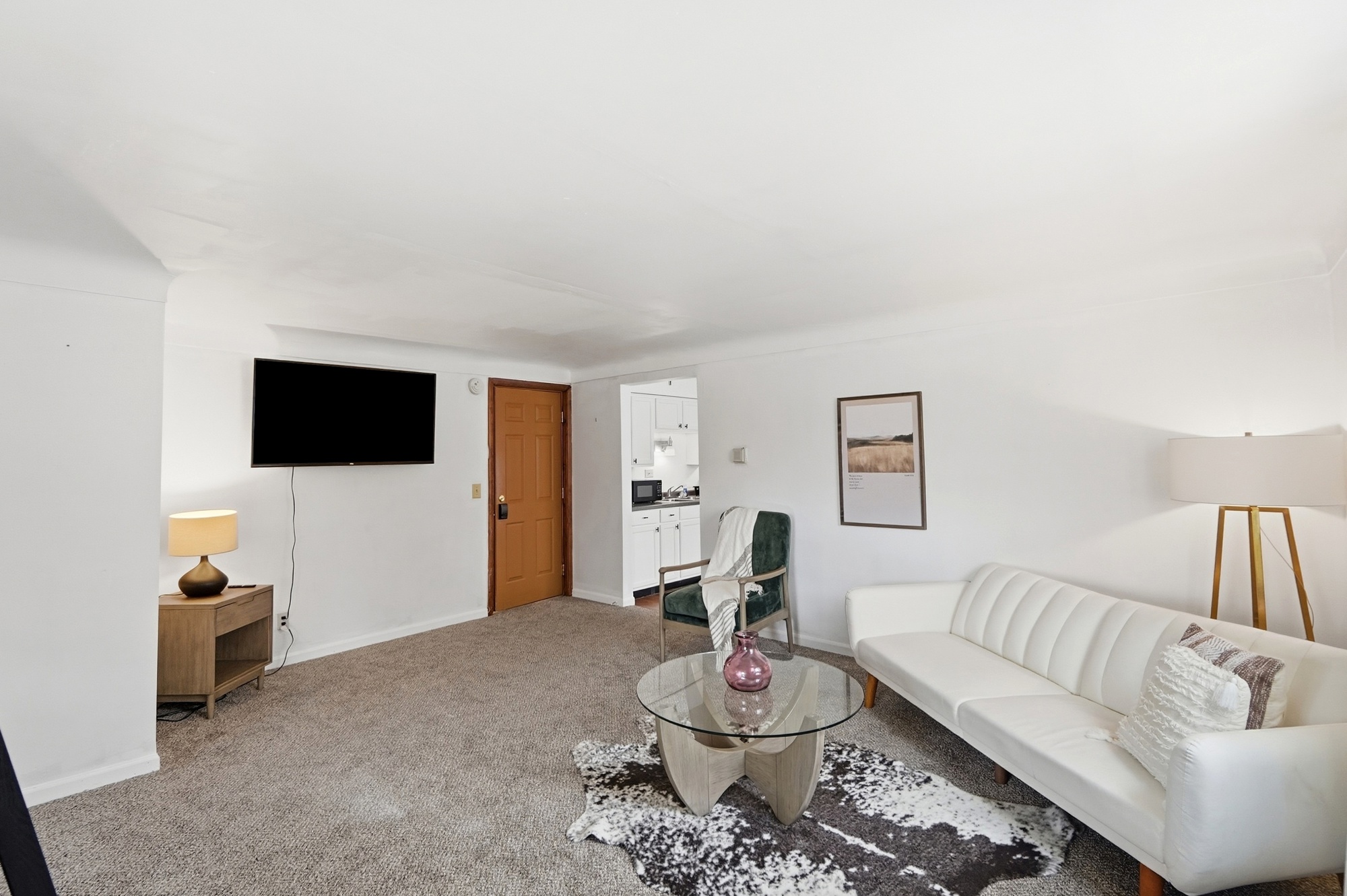 Bright, cozy living room with TV, stylish seating, and easy kitchen access