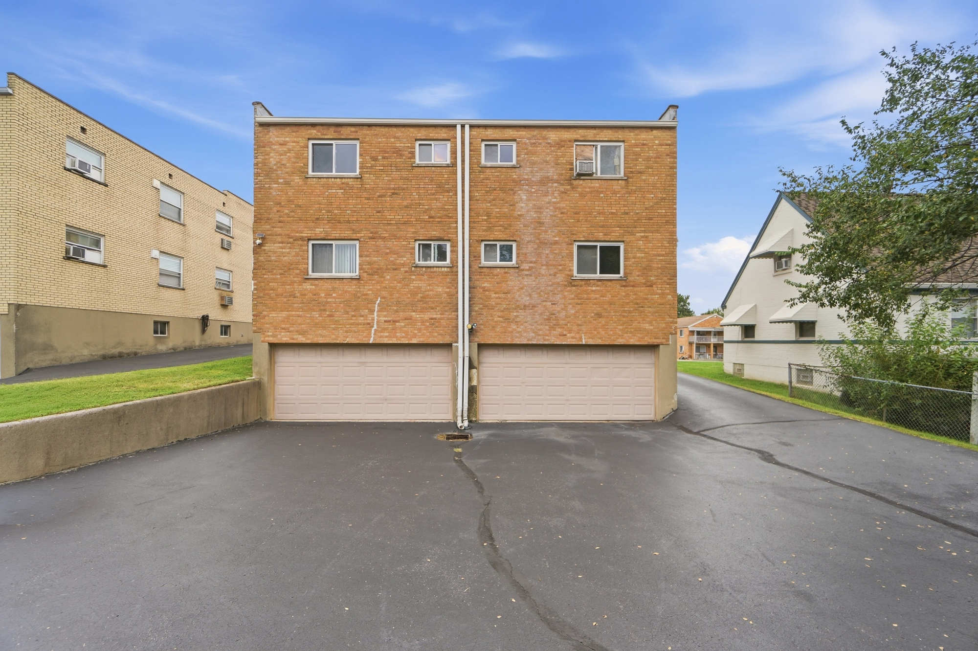 Brick exterior with attached garages and spacious driveway parking