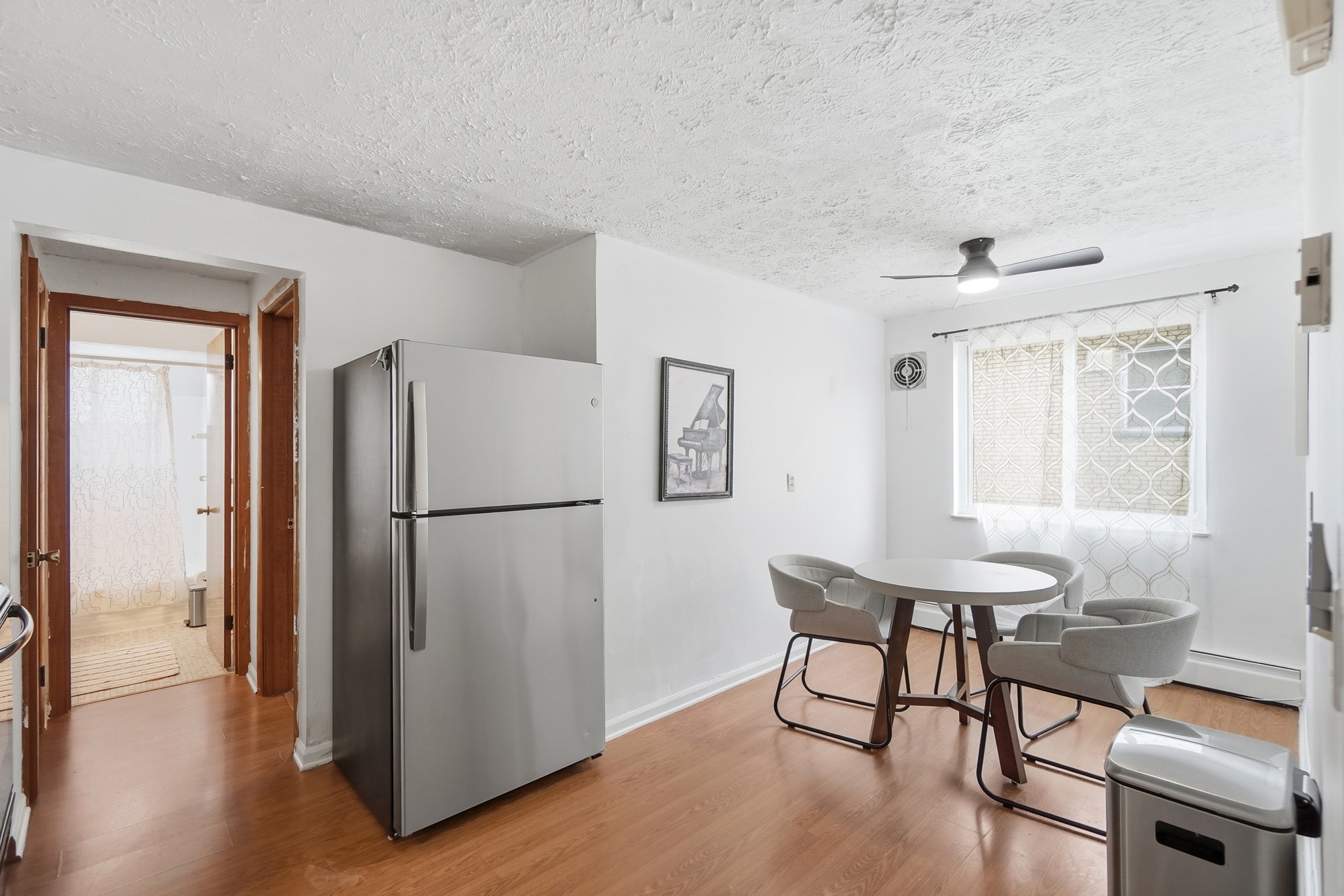 Bright dining nook with natural light, modern seating, and full-size fridge
