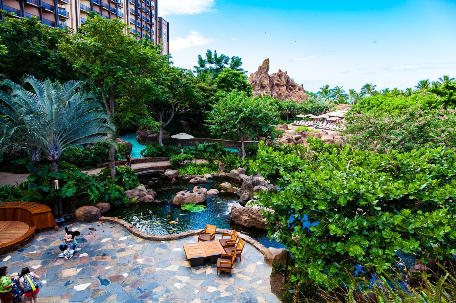 Lush tropical courtyard with koi pond, patio seating, and resort-style views