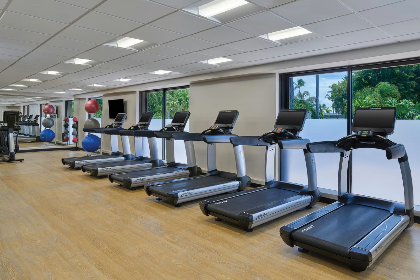 Bright on-site fitness room with treadmills and lush window views