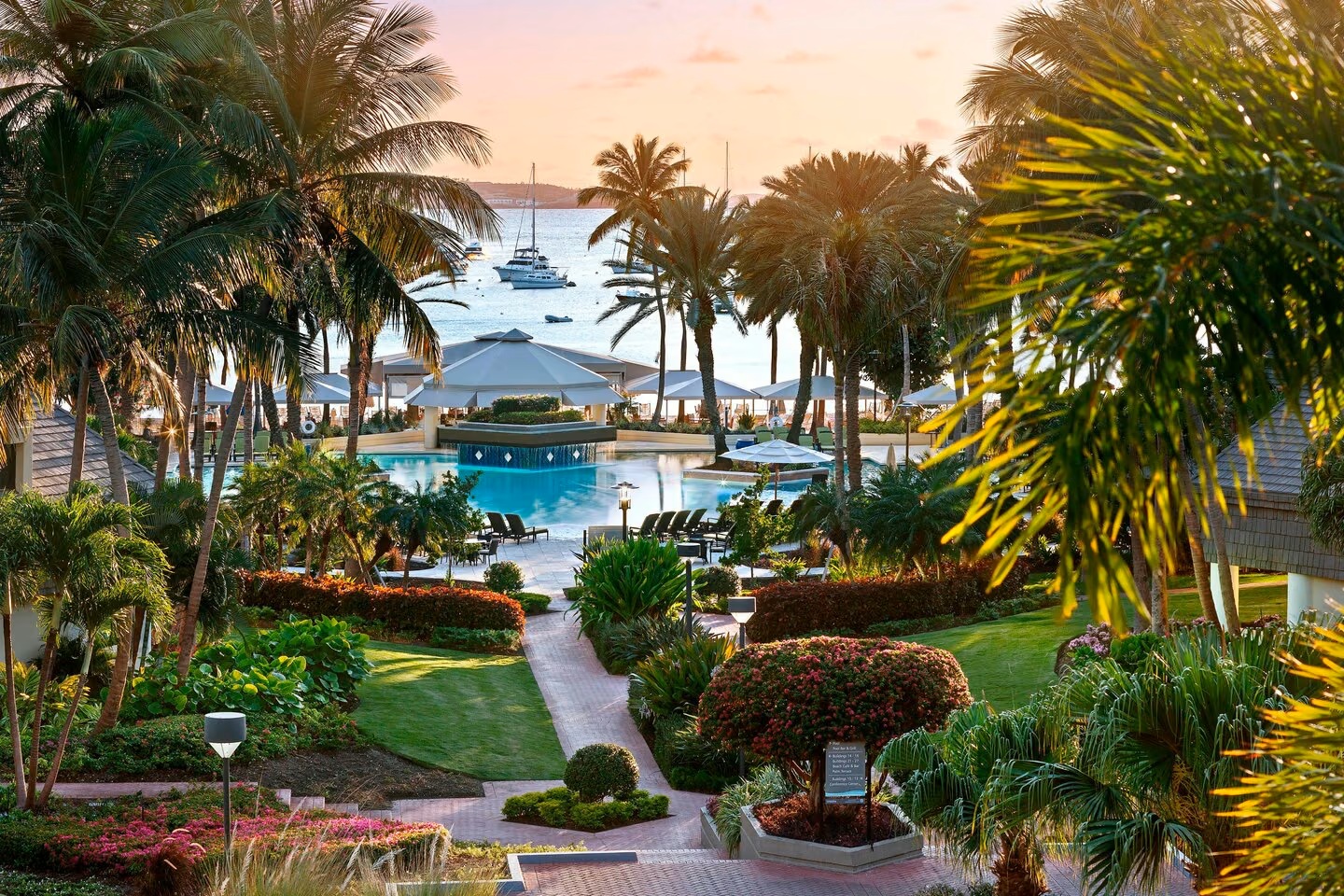 Tropical pool oasis with palm-lined paths and stunning waterfront views