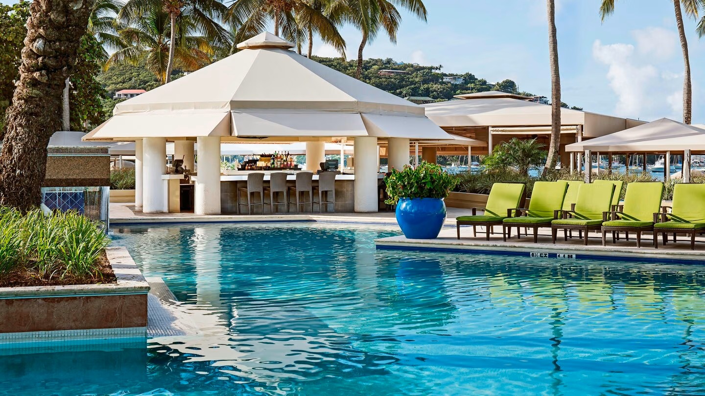 Tropical pool oasis with swim-up bar and palm-lined lounge seating
