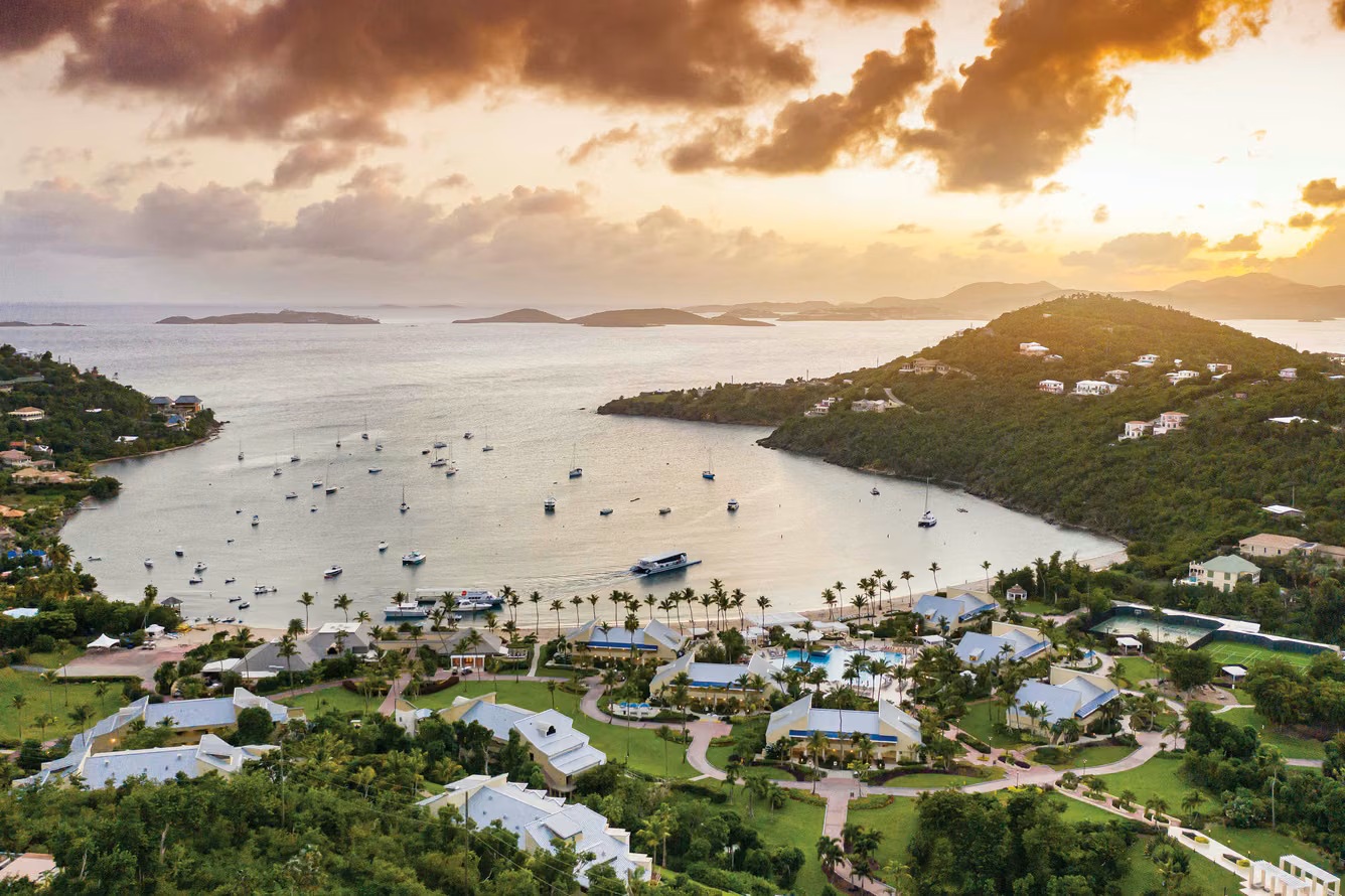 Sweeping sunset bay views with lush tropical grounds and anchored sailboats