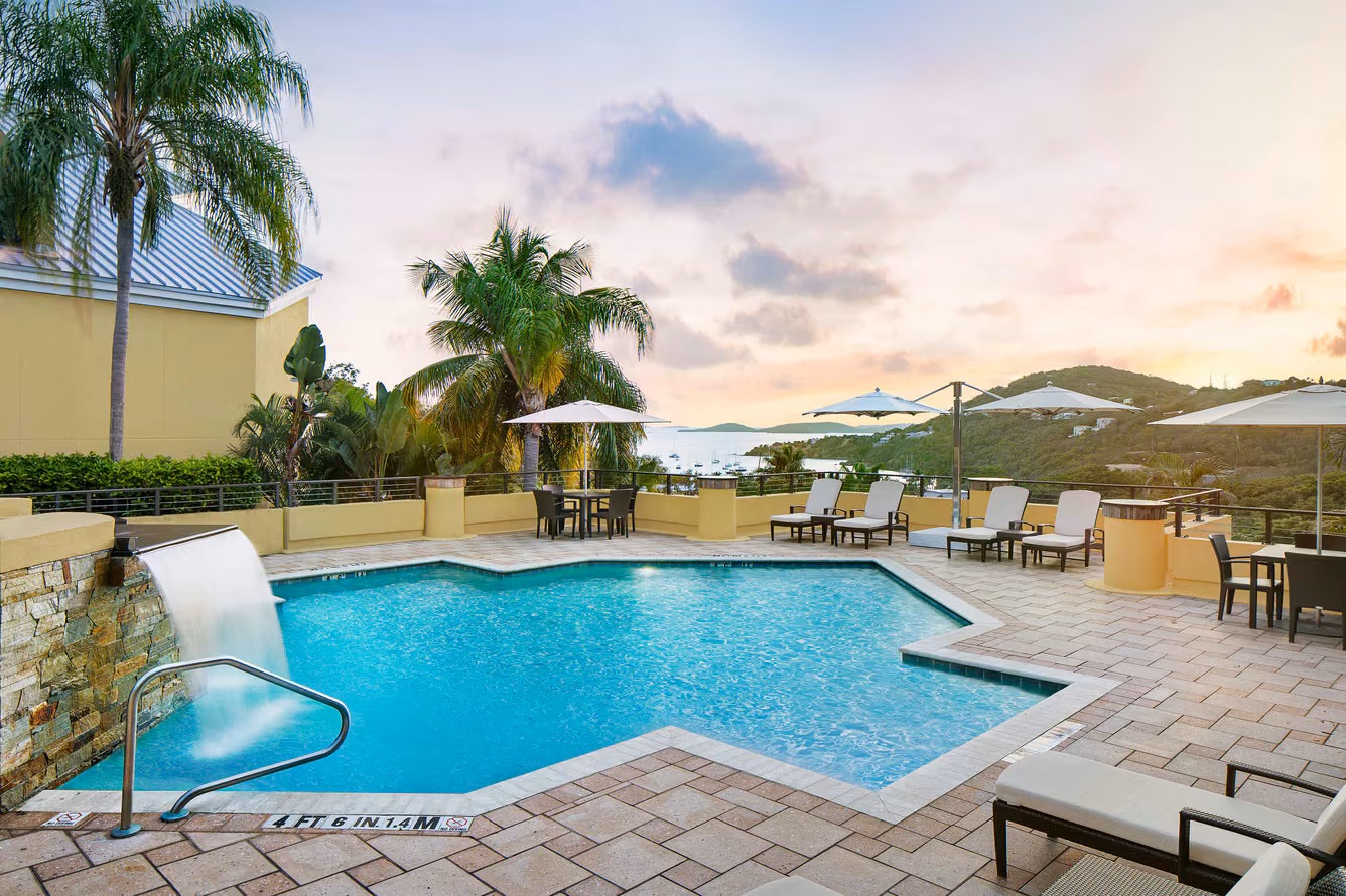 Resort-style pool with waterfall, sunset views, and tropical lounging