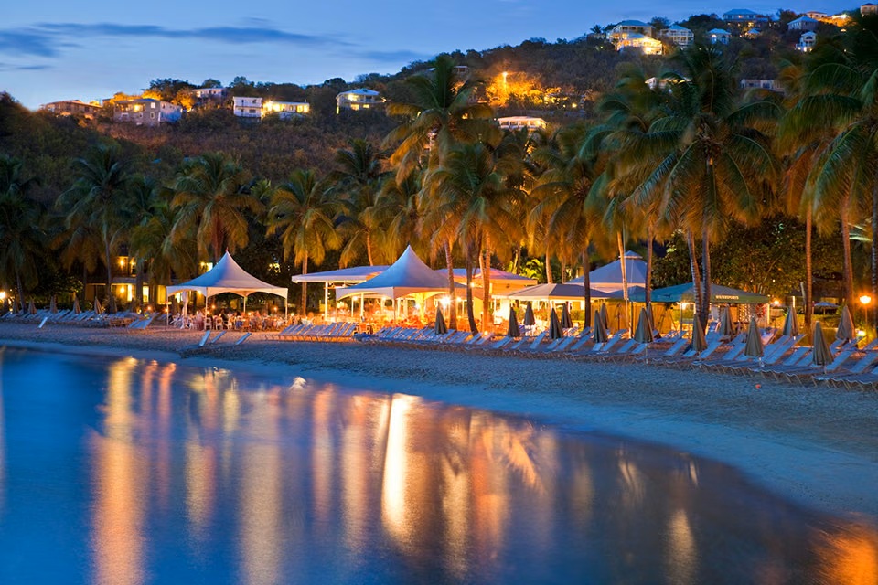 Palm-lined beachfront at dusk with glowing lights and serene tropical views