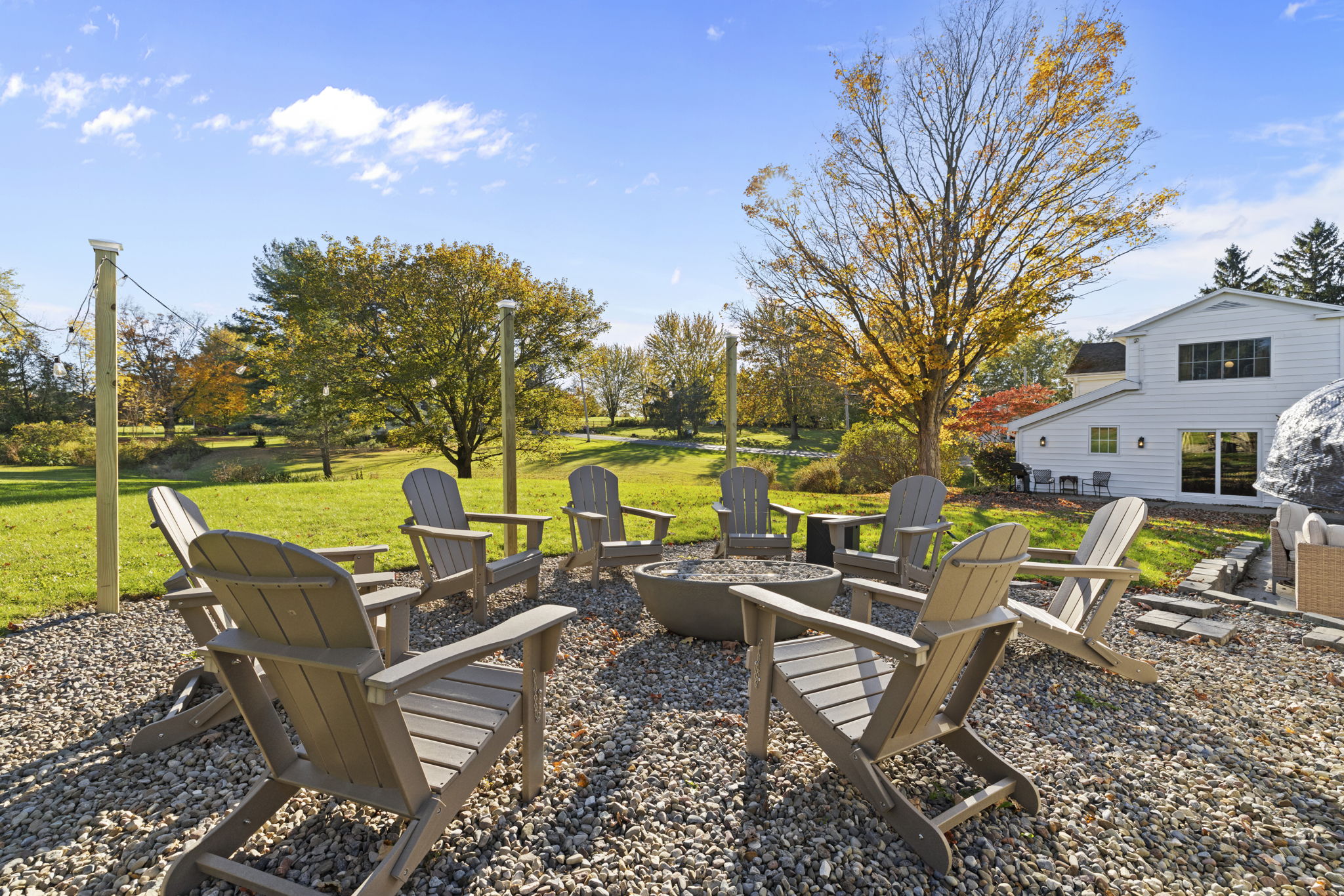 Spacious backyard fire pit patio with Adirondack seating and scenic views